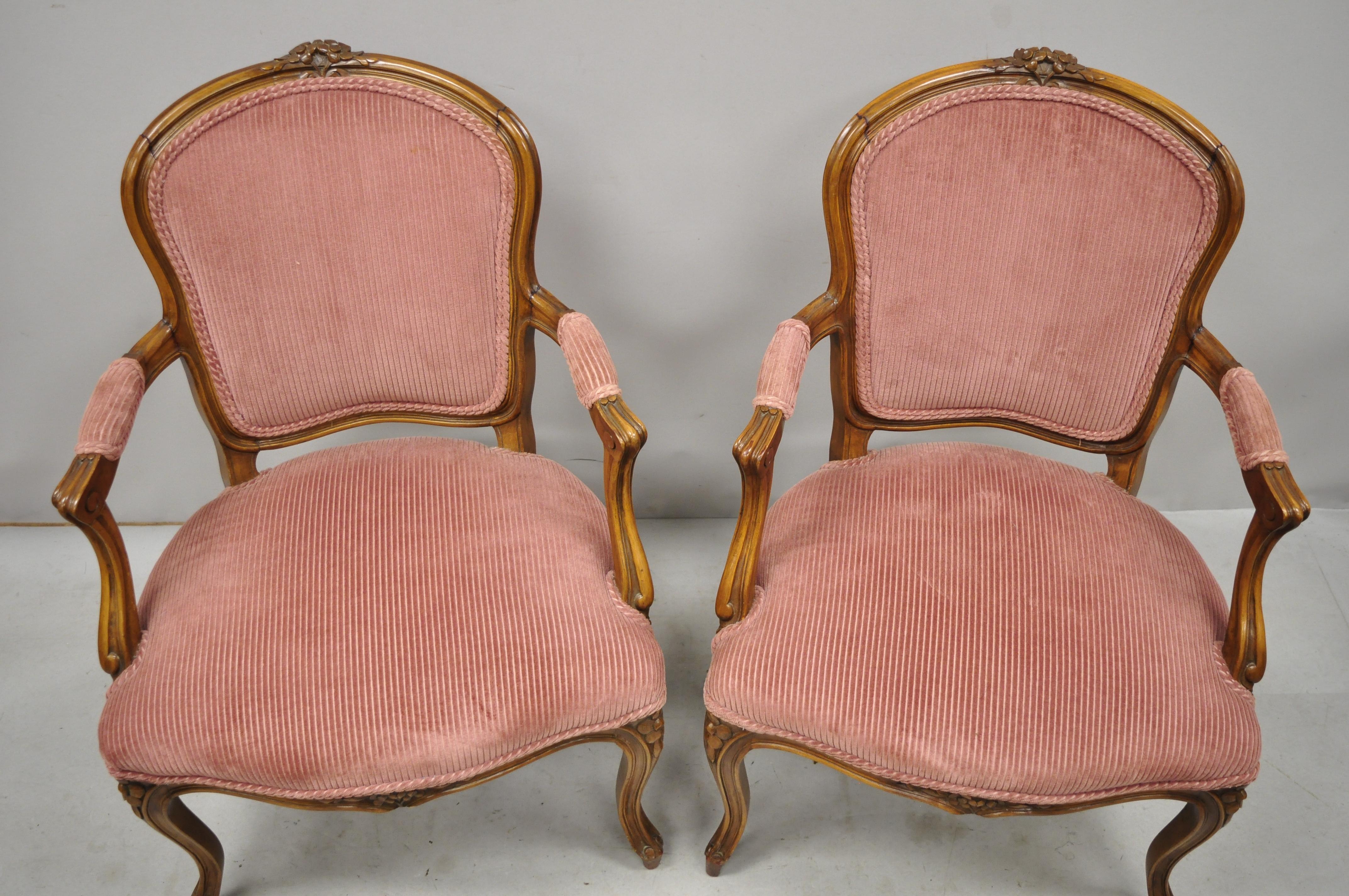 Pair of antique French Provincial Louis XV style carved walnut small armchairs. Item features nice smaller size, pink corduroy upholstery, flower carved crest, solid wood frame, upholstered armrests, nicely carved details, cabriole, great style and