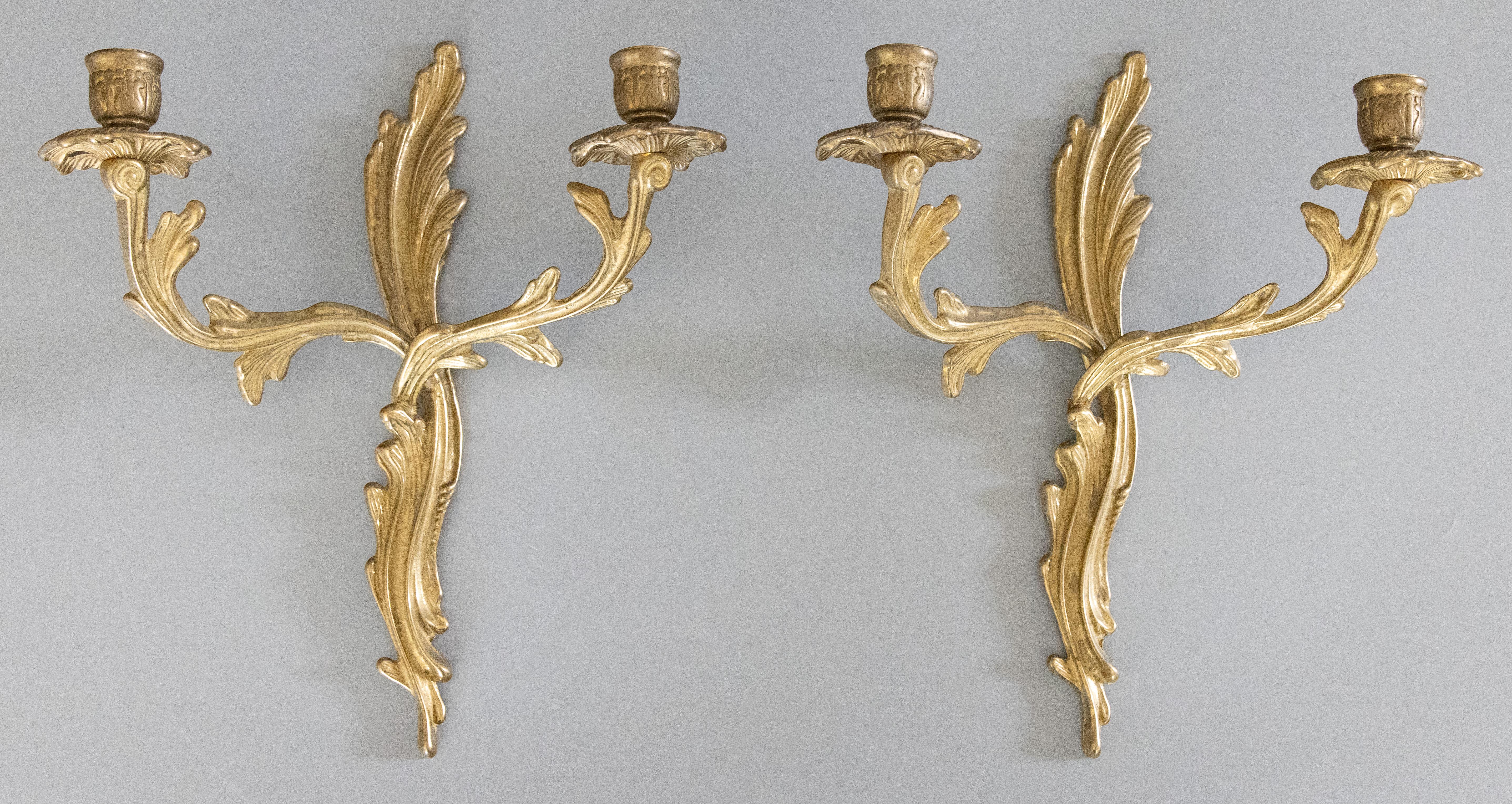 A gorgeous pair of antique French Rococo style gilt brass candelabra two arm candle wall sconces. These beautiful sconces are solid and heavy with gilt scrolls and acanthus leaves in a lovely gilt patina.

DIMENSIONS
11ʺW × 5.25ʺD × 13.25ʺH
