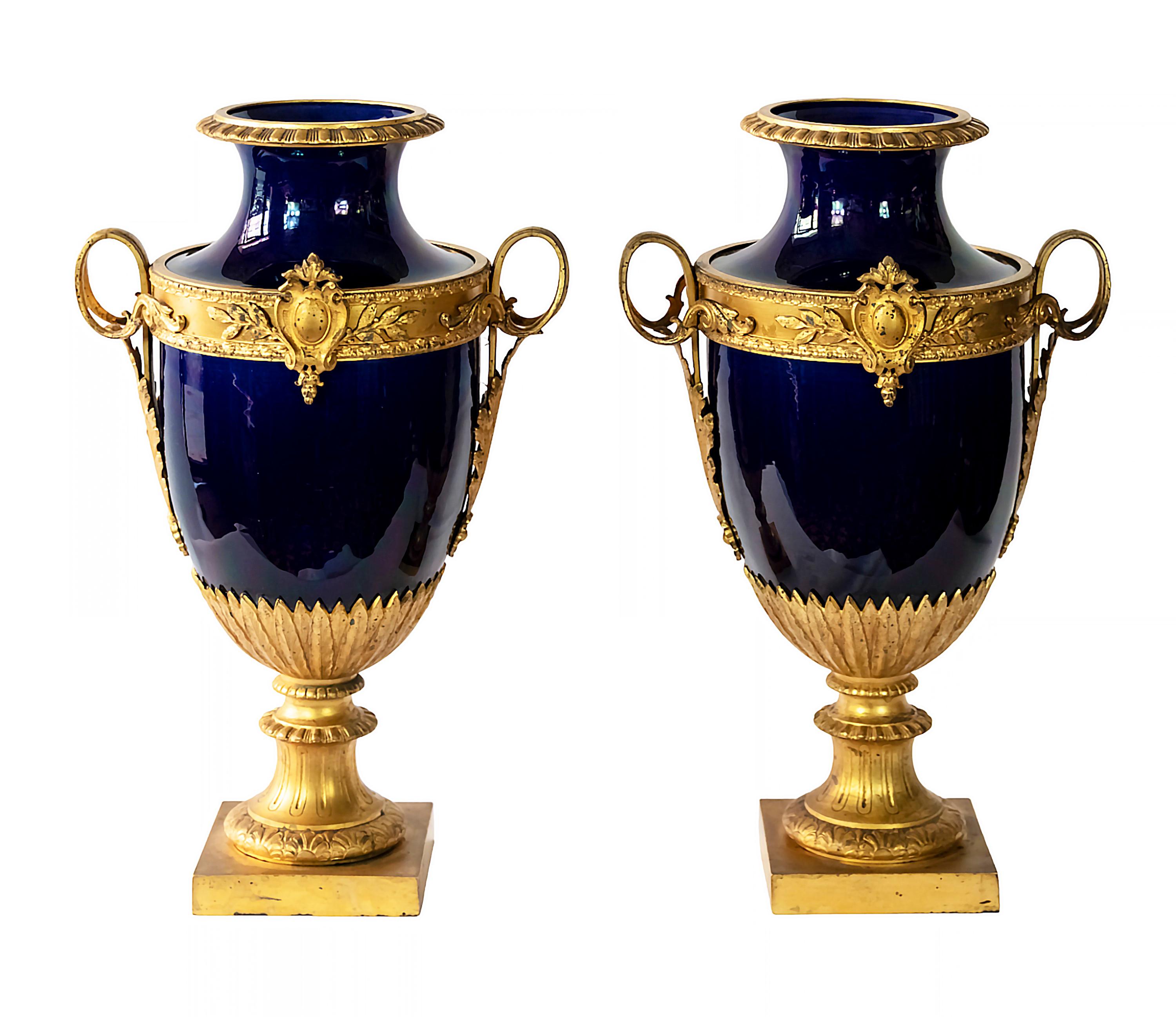 Pair of antique French Sevres style glazed cobalt blue decorative vases on the gilt bronze base and decorative details mounted all over the porcelain.