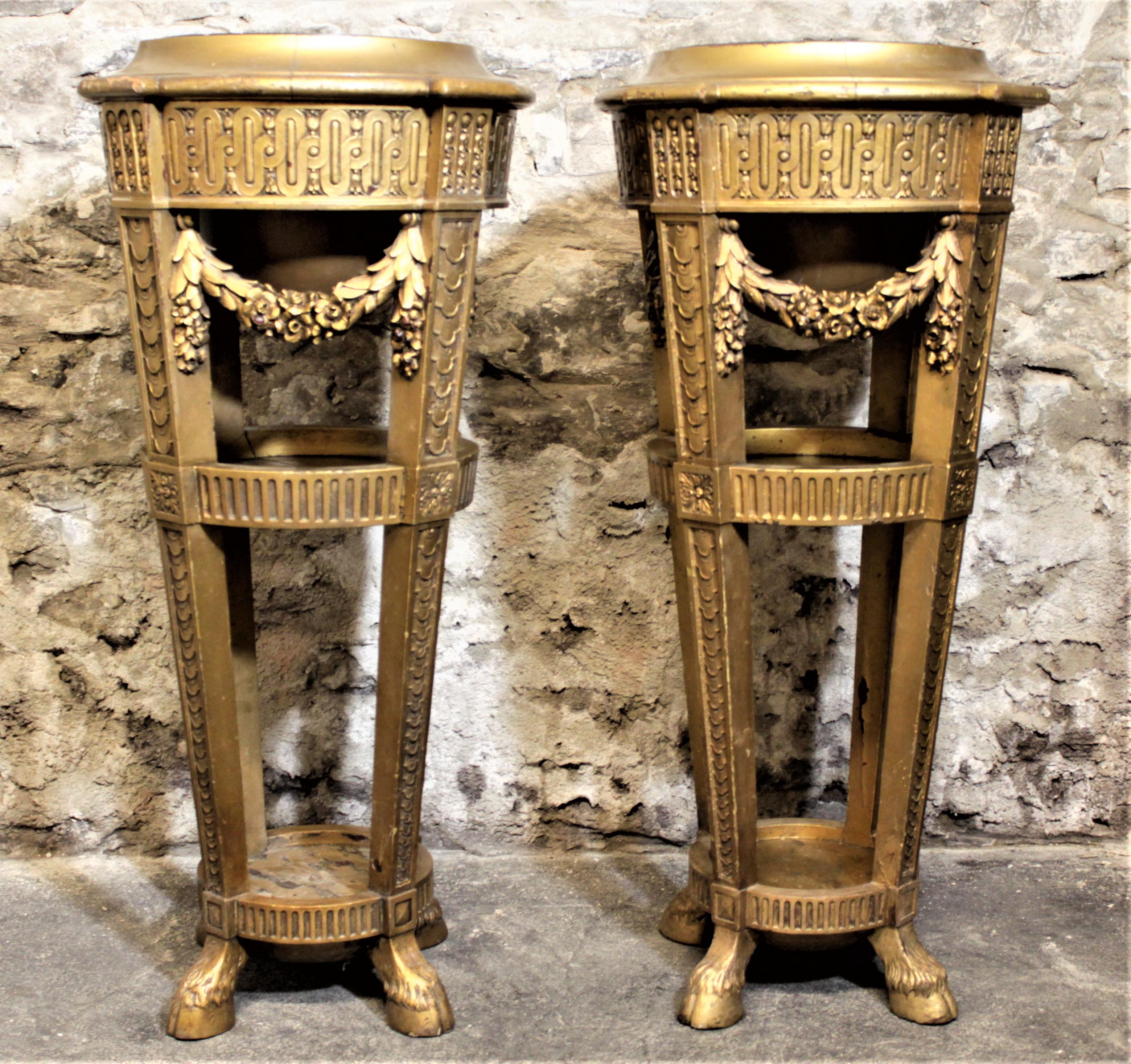 This antique pair of carved wooden plant stands or pedestals were most likely made in Europe in the Late Victorian era. The stands are composed of a sturdy softwood that has been intricately carved, featuring geometric designs on the legs, accented