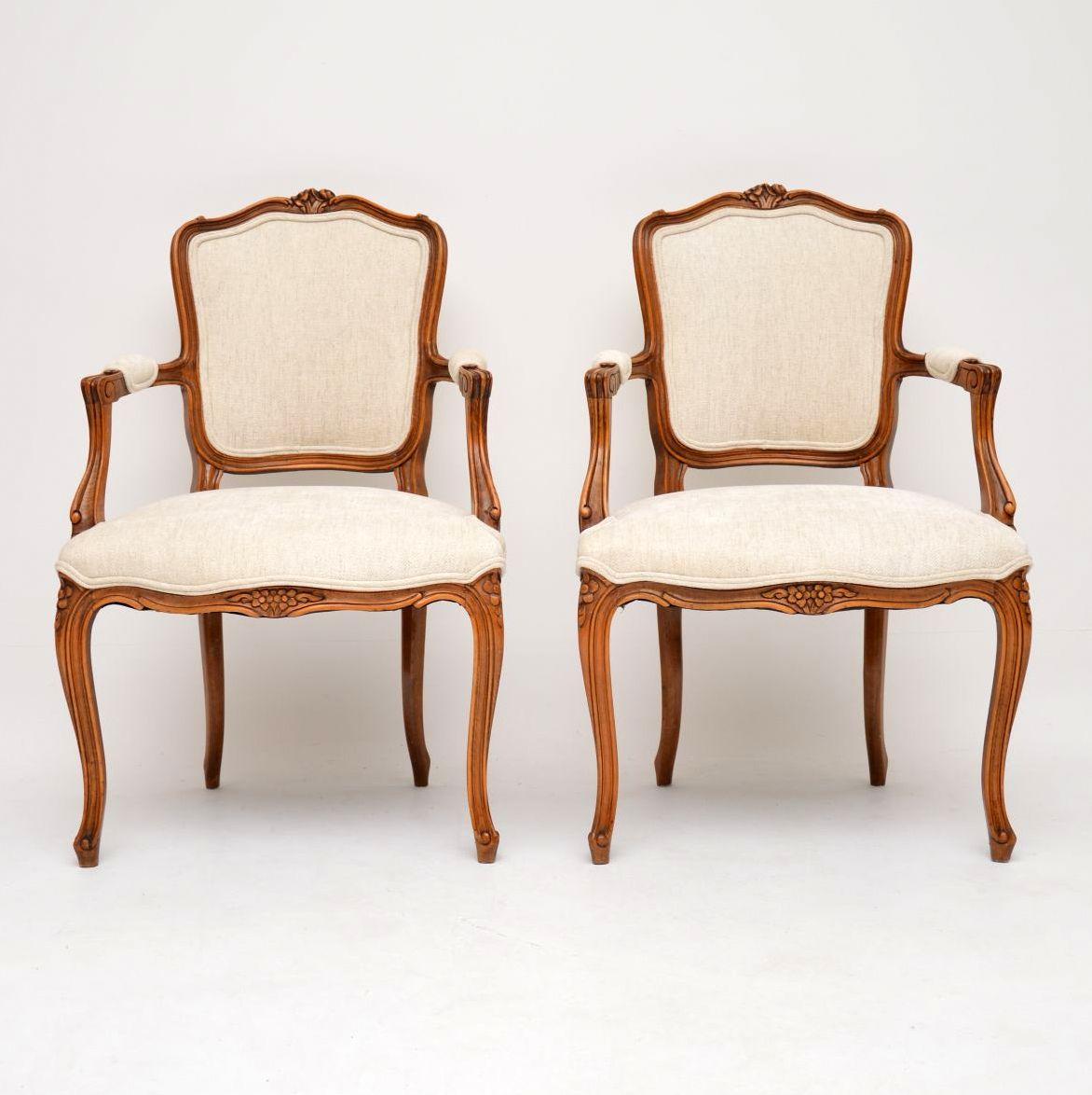 Pair of antique French walnut salon armchairs that have just been re-upholstered in our very popular cream textured fabric, with double piping. The curvaceous walnut frames have good carvings all over & they are structurally sound too. These