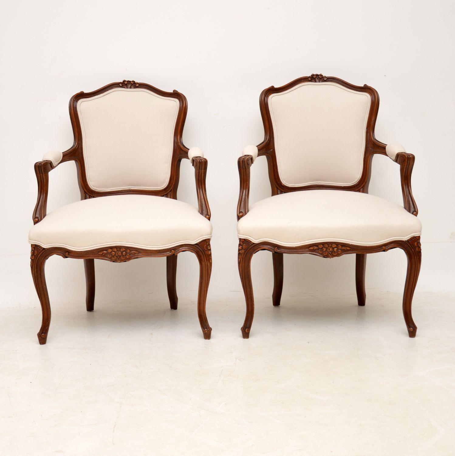 Pair of antique French open arm walnut salon armchairs with well carved frames and in very good condition, dating to circa 1920s period. They are strong, sturdy and comfortable, having just been professionally re-upholstered in our very popular