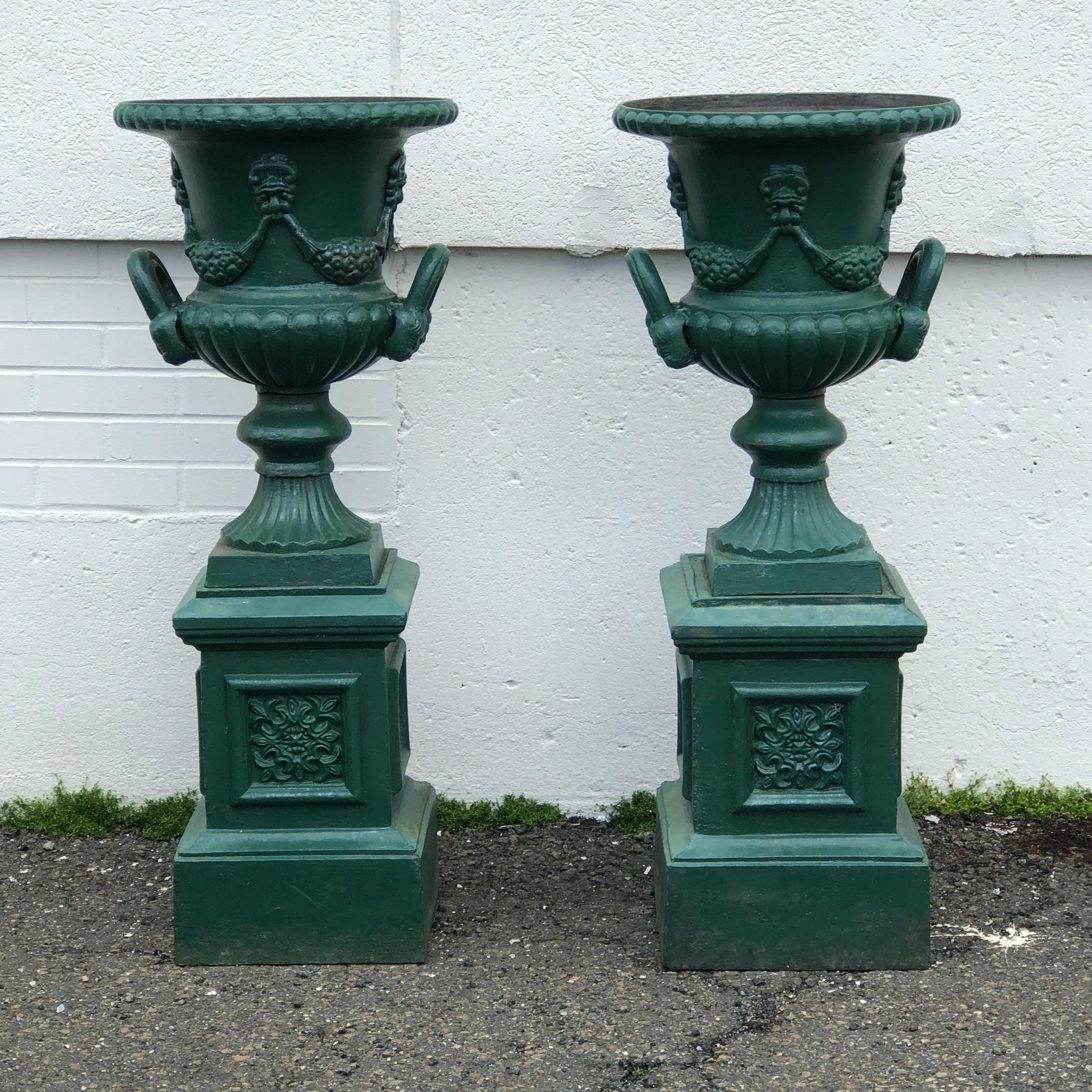 Pair of fine Antique Cast iron Garden Urns, all original including plinths, of Medici shape with handles and décor of garlands and masks.