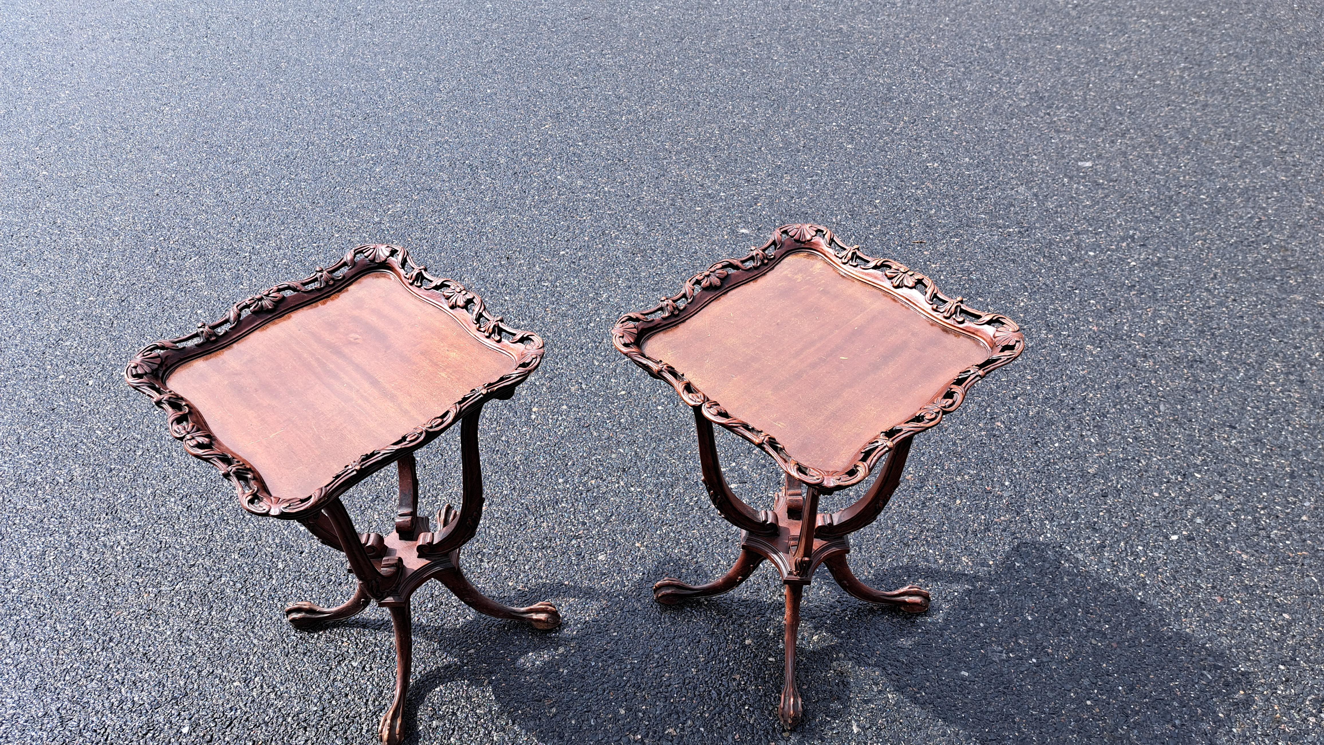 Pair of George III style mahogany side tables with four paw feet and carved details including open carving framing the table tops.