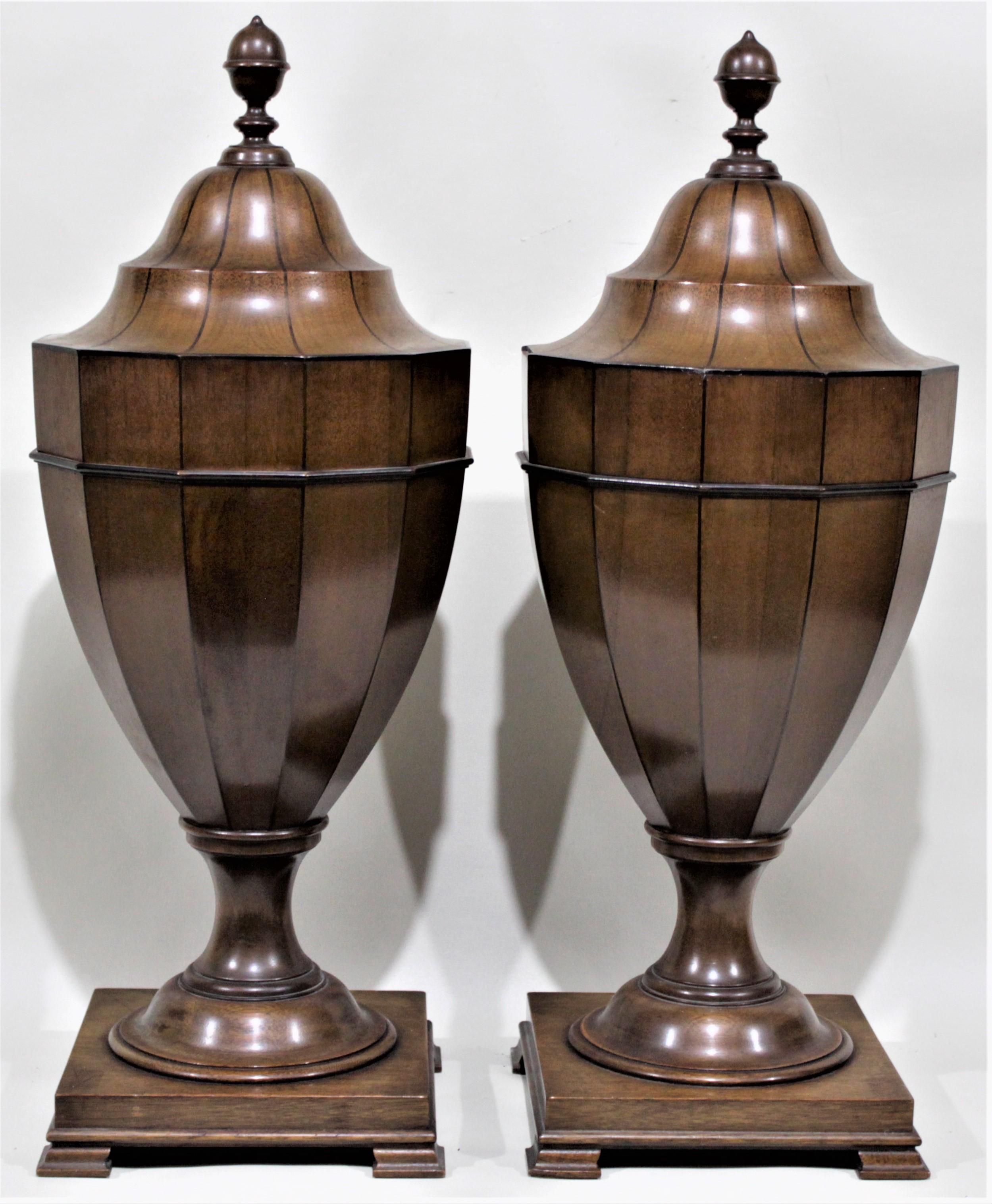 This matched pair of solid mahogany knife urns were made in the Georgian style, presumably in the United States during the 1930s. Each finial functions as a handle to raise the top to expose the storage for knives. The urns each sit on a footed
