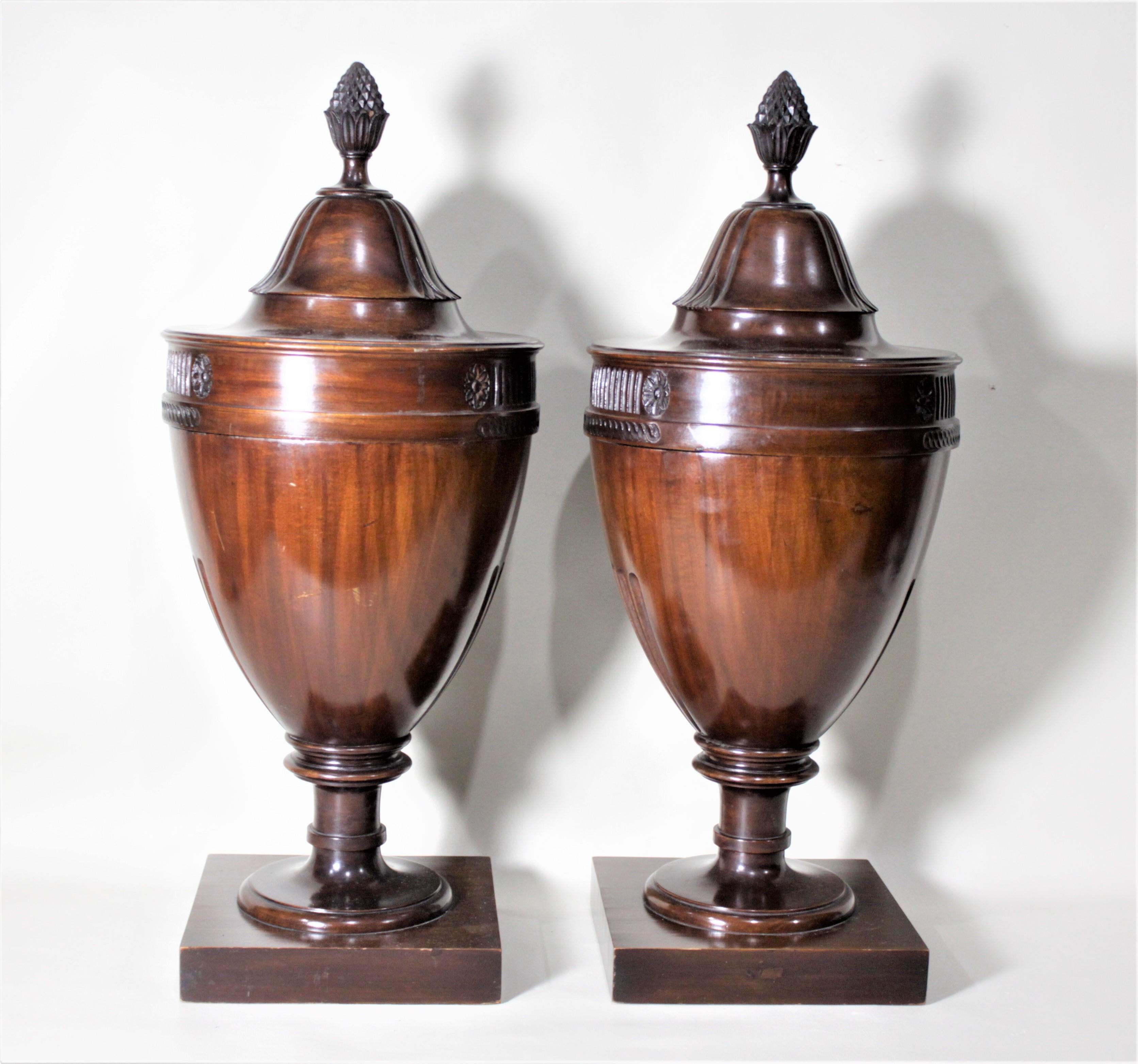 This matched pair of solid mahogany knife urns were made in the Georgian style, presumably originating from England during the Edwardian period. These knife urns show carved accents on the top, base, and finial. Each finial functions as a handle to