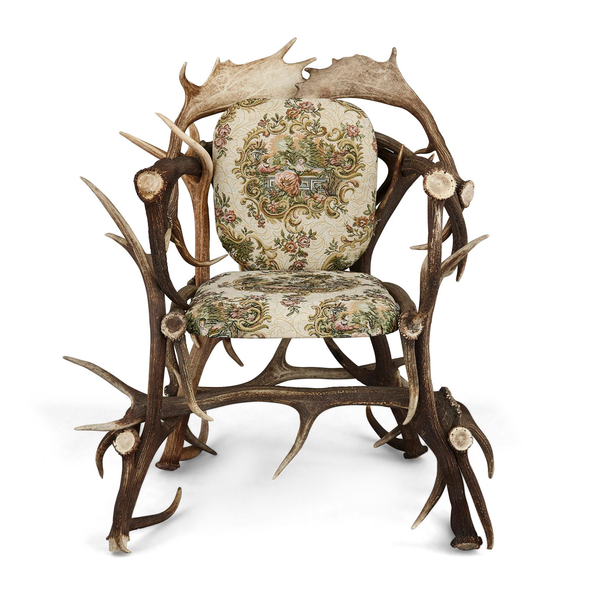 Pair of antique German Antler chairs with rococo style upholstery.
German, early 20th century
Dimensions: Height 108cm, width 212cm, depth 80cm

These unusual chairs, an example of 'antler-seat furniture', were likely crafted in Germany in the
