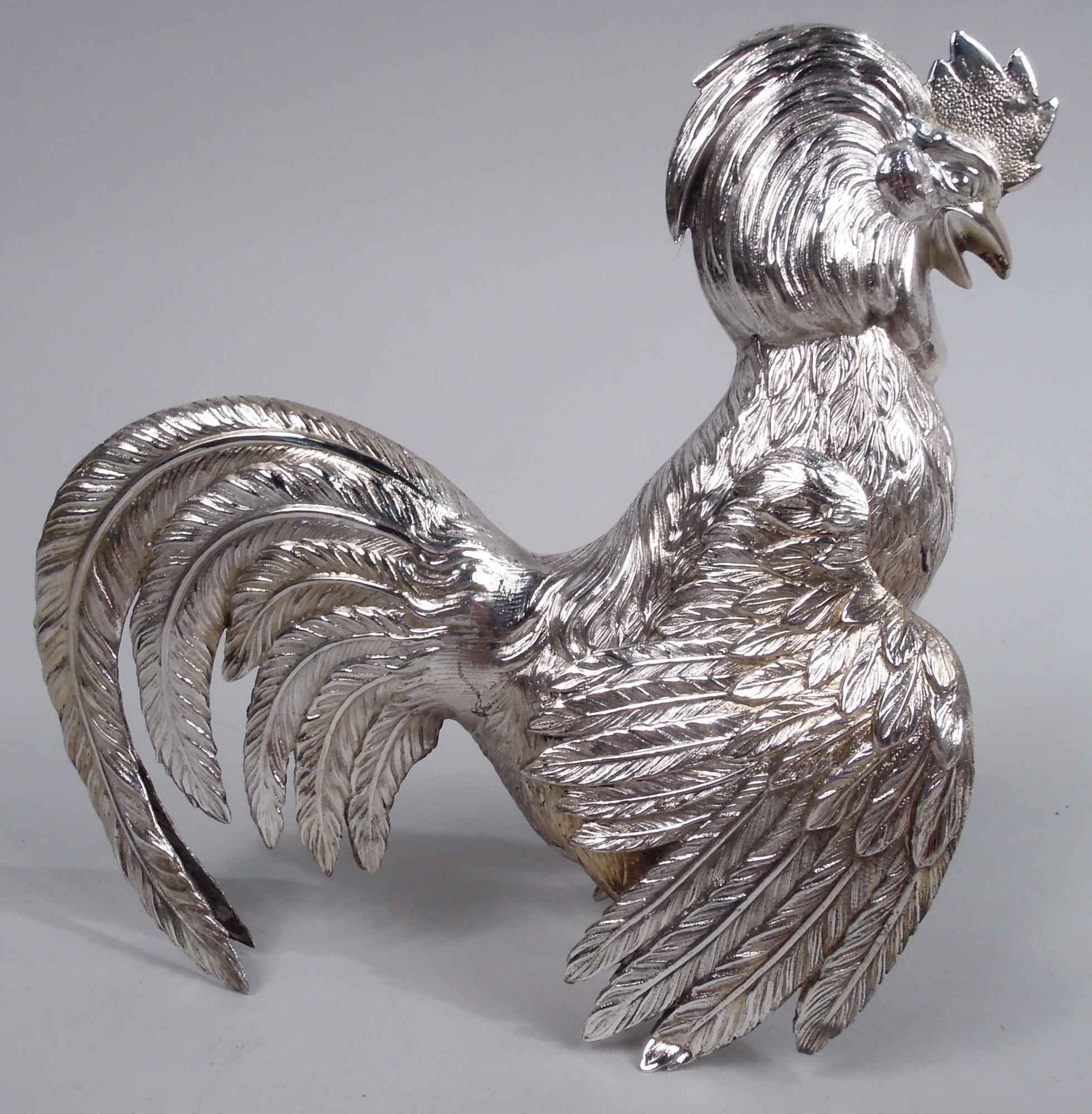 Pair of German silver birds, ca 1920. A rooster and hen with downturned wings and flamboyant flouncy tails. The rooster has a shaggy crown and raised talon and looks down while the hen, who has a small trim crown and scaly wattles, looks up. Cawing