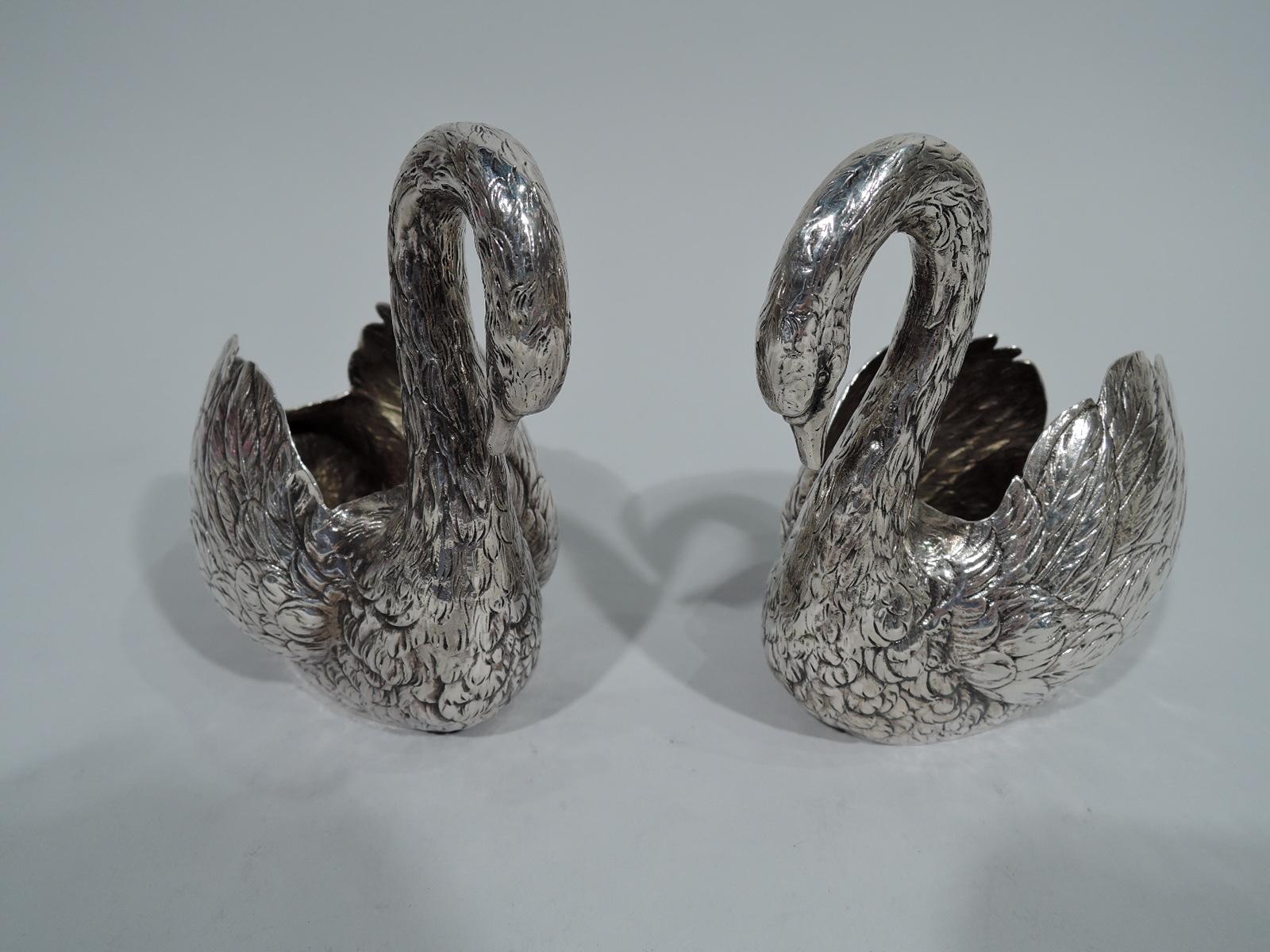 Pair of German 800 silver swans, circa 1900. Each: Puffed-out wings, vertical tail, and s-scroll neck terminating in closed bill. Interior gilt washed. An elegant pair to glide down the table. Hollow for holding treats. Hallmarked. Total weight: