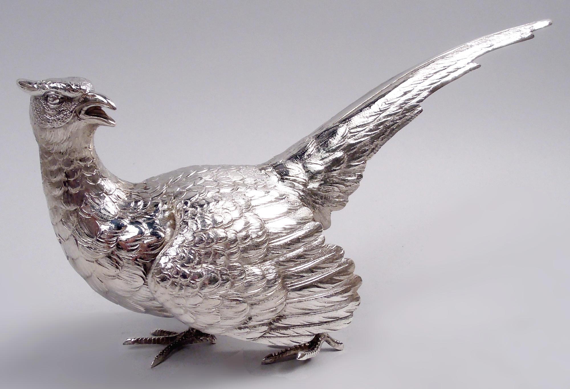 Coppia di fagiani tedeschi in argento 800, 1910 circa. Un gallo e una gallina si pavoneggiano lungo il tavolo su artigli squamosi con becchi gracchianti e teste girate in allarme. Il gallo si abbassa mentre la gallina si dimena freneticamente.