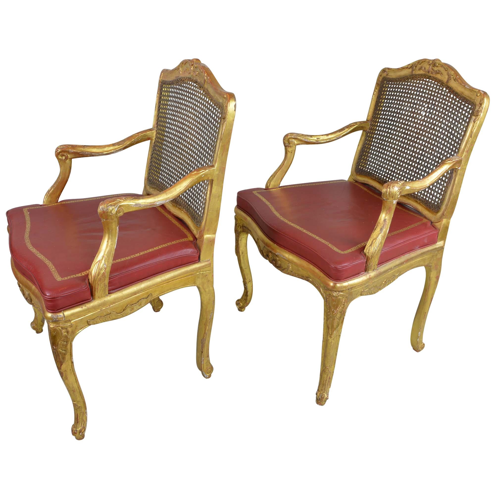 Classic Regency scroll arms of these chairs are in a stunning gold. Leather cushions have gold accents adding to the richness. There backs feature the cane detail - small hole in caning in one. The chairs are of a fine design but are in excellent