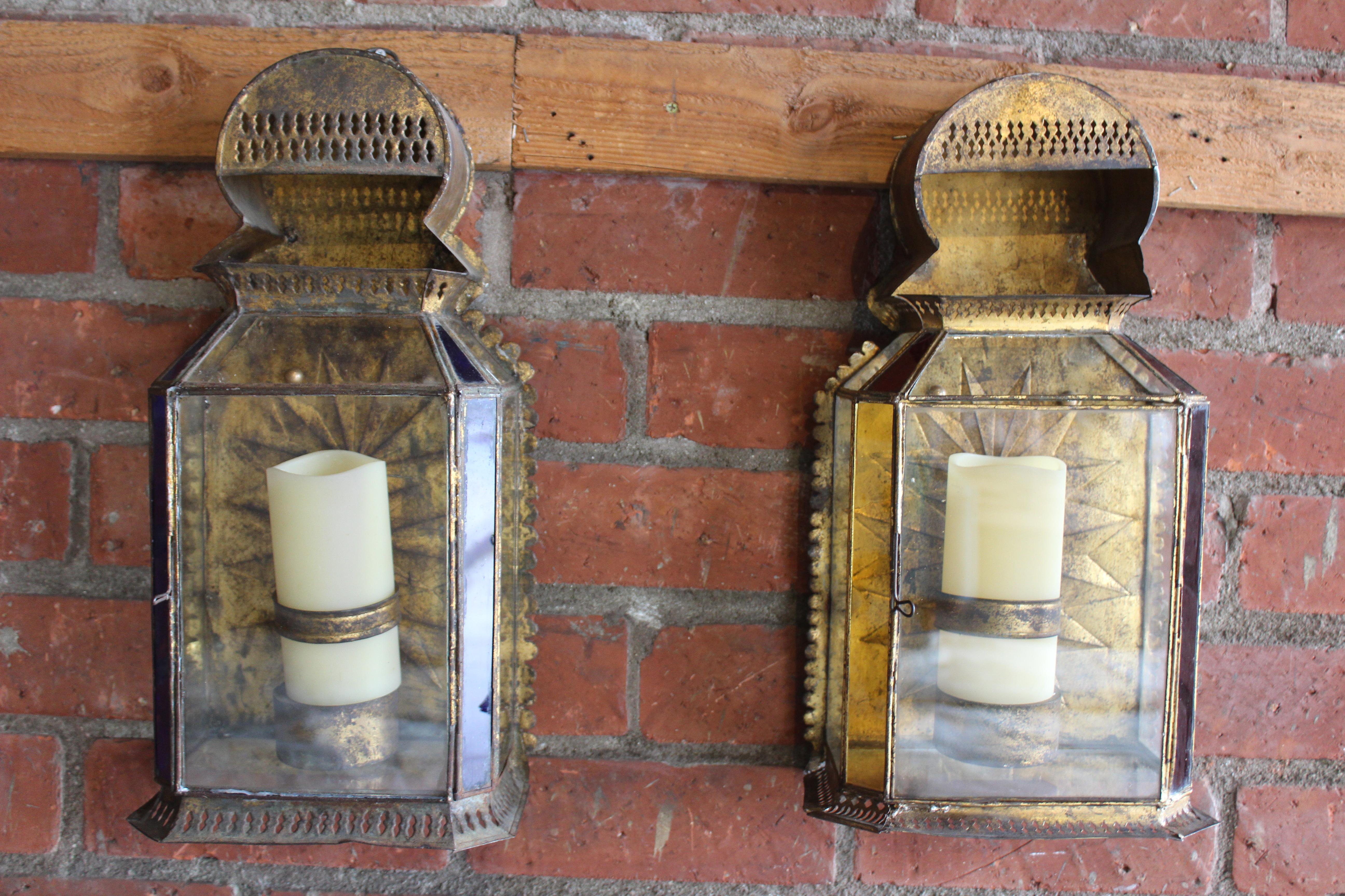 Pair of antique gilt metal Moroccan Moorish style wall sconces. The pair have been professionally rewired and restored. They include resin candle covers that resemble wax. They are ready for installation. They both have glass faceted fronts and