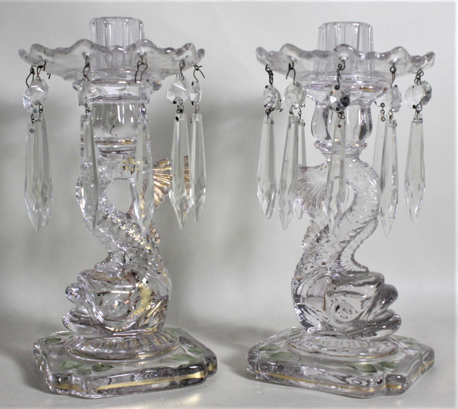 This pair of clear glass figural dolphin lustres are unsigned, but presumed to have been made in Italy in circa 1900 in the Victorian style. These candle holders are made of heavy molded clear glass and depict detailed stylized dolphins with gilt