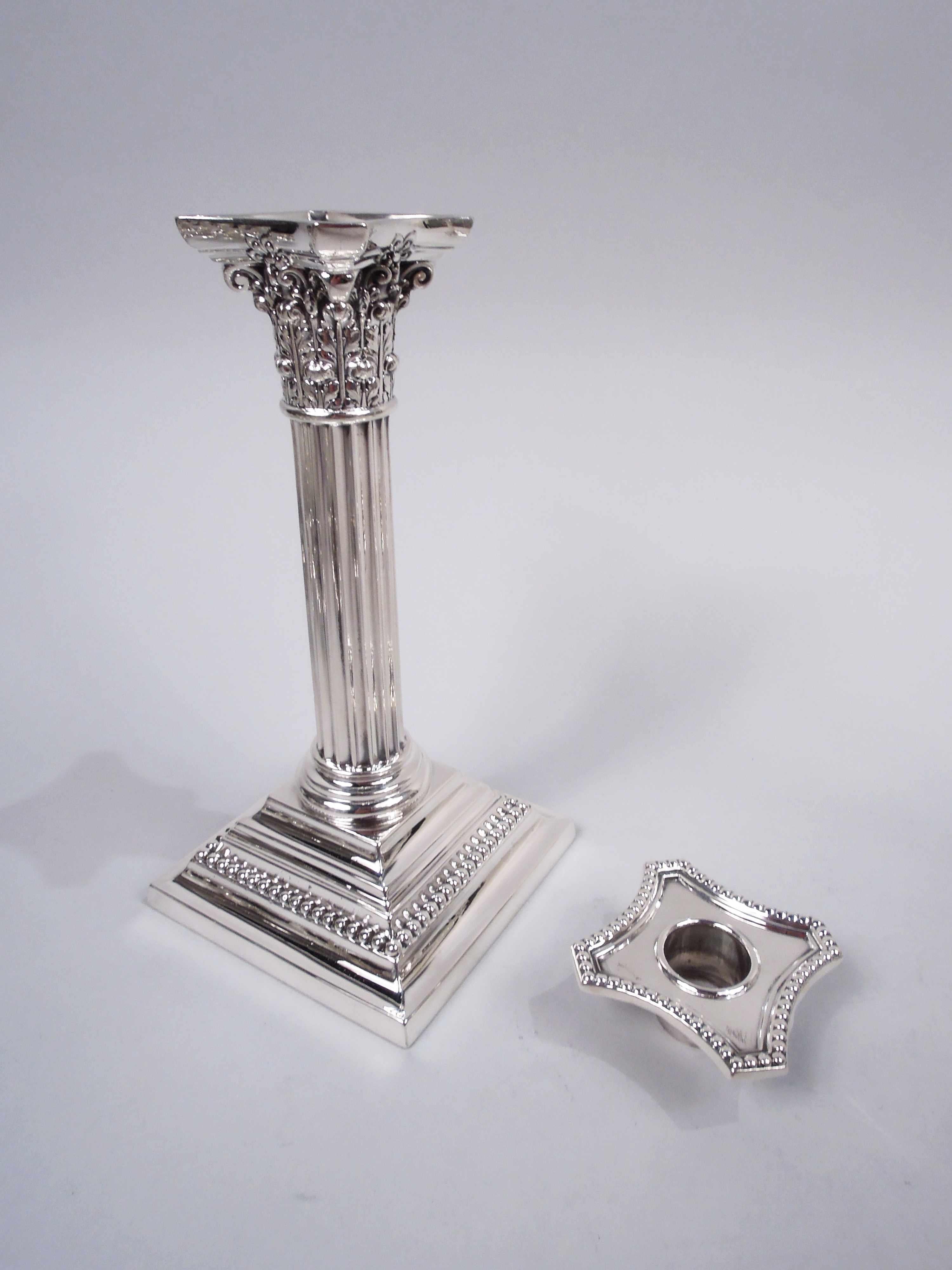 Pair of Edwardian Classical sterling silver column candlesticks. Made by Gorham in Providence in 1911-15. Each: Column with fluted shaft on stepped square base. Corinthian capital with chamfered and concave bobeche. Beading. Fully marked including
