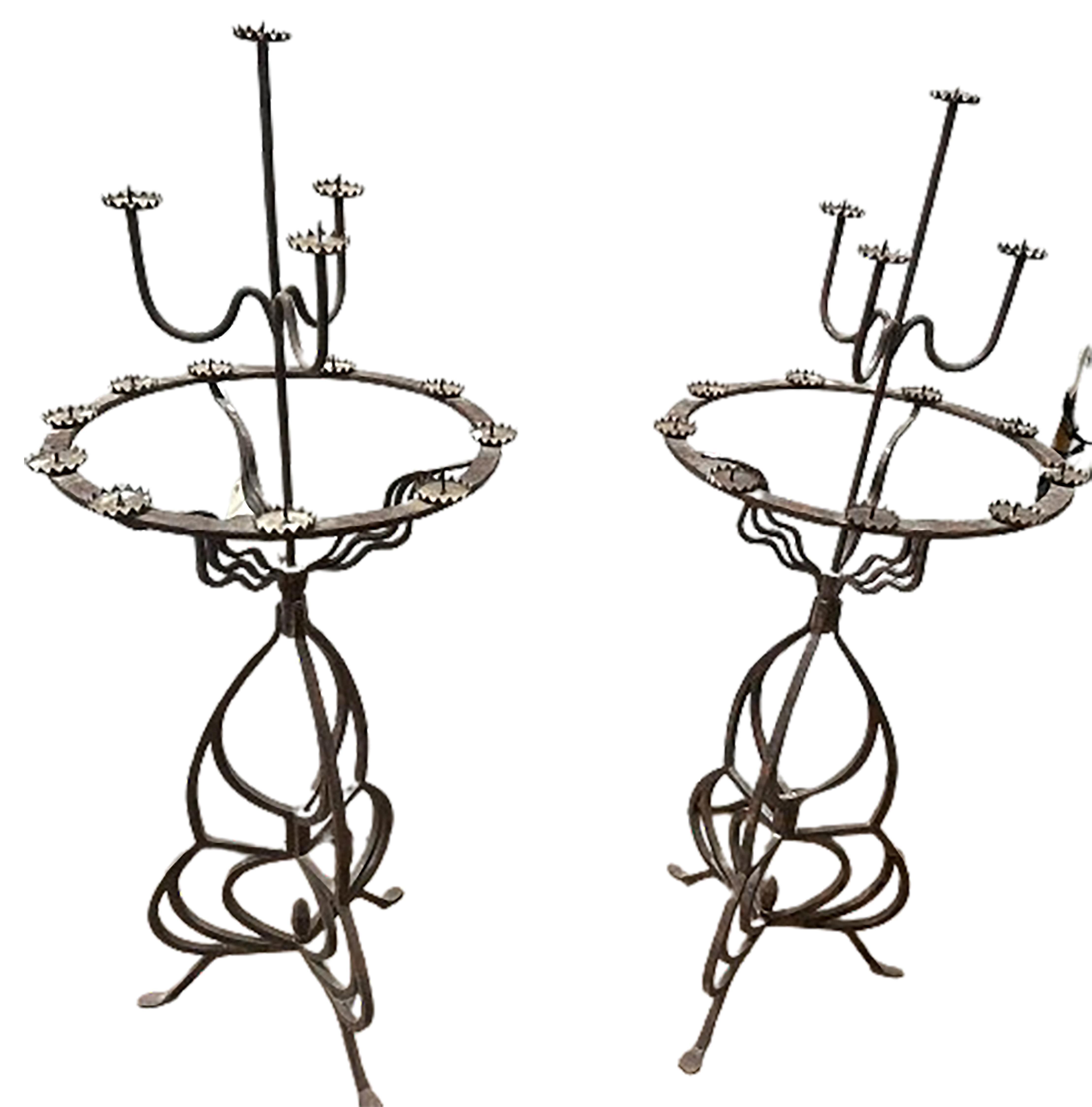 A handsome pair of antique gothic style pedestal candelabra torcheres. Made of wrought iron. Contains 13 candle holders at three different levels. The upper level is supported by wave pattern iron bars. The base is made up of intricate designs that