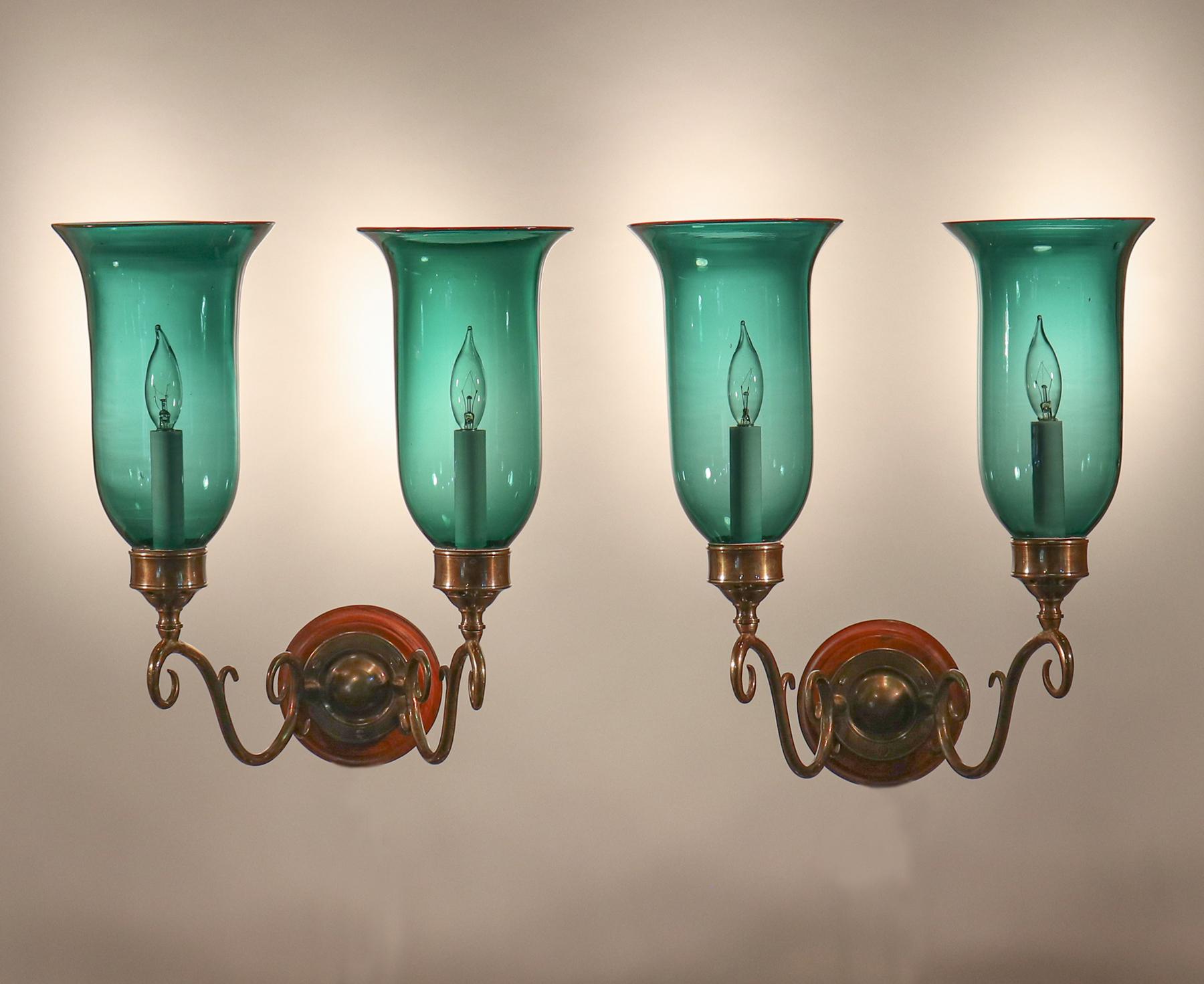 A set of four well-matched, gracefully flared hurricane shades from England, circa 1900. These subdued green shades are of very good quality, with desirable air bubbles and waviness in the hand blown glass. Originally for candles, the sconces have