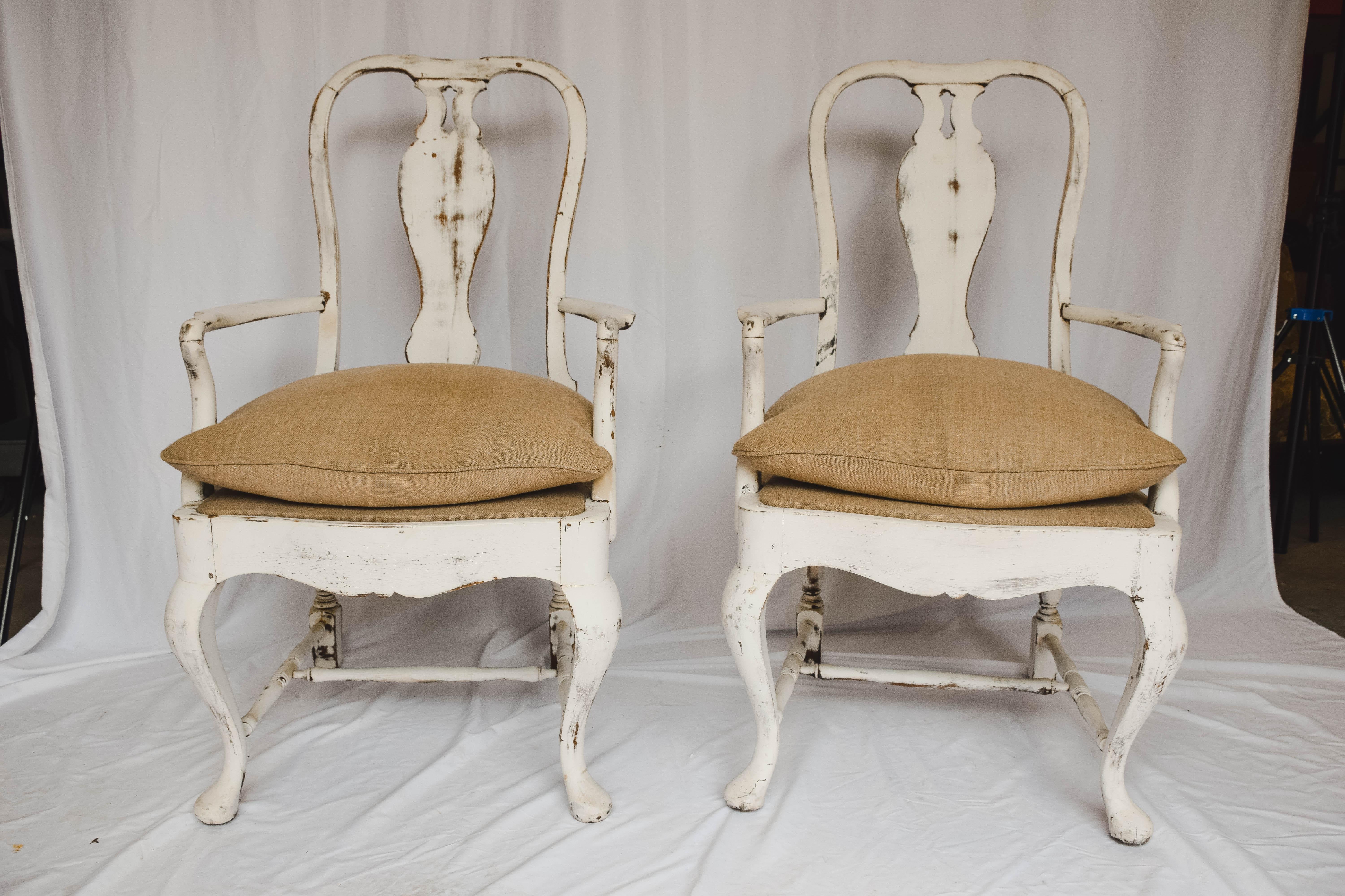 This lovely pair of Swedish arm chairs were likely from a Swedish farm house. The two armchairs have been painted white and lightly scraped creating a nice contrast with the darker wood beneath. The chairs with beautifully curved backs and arms and