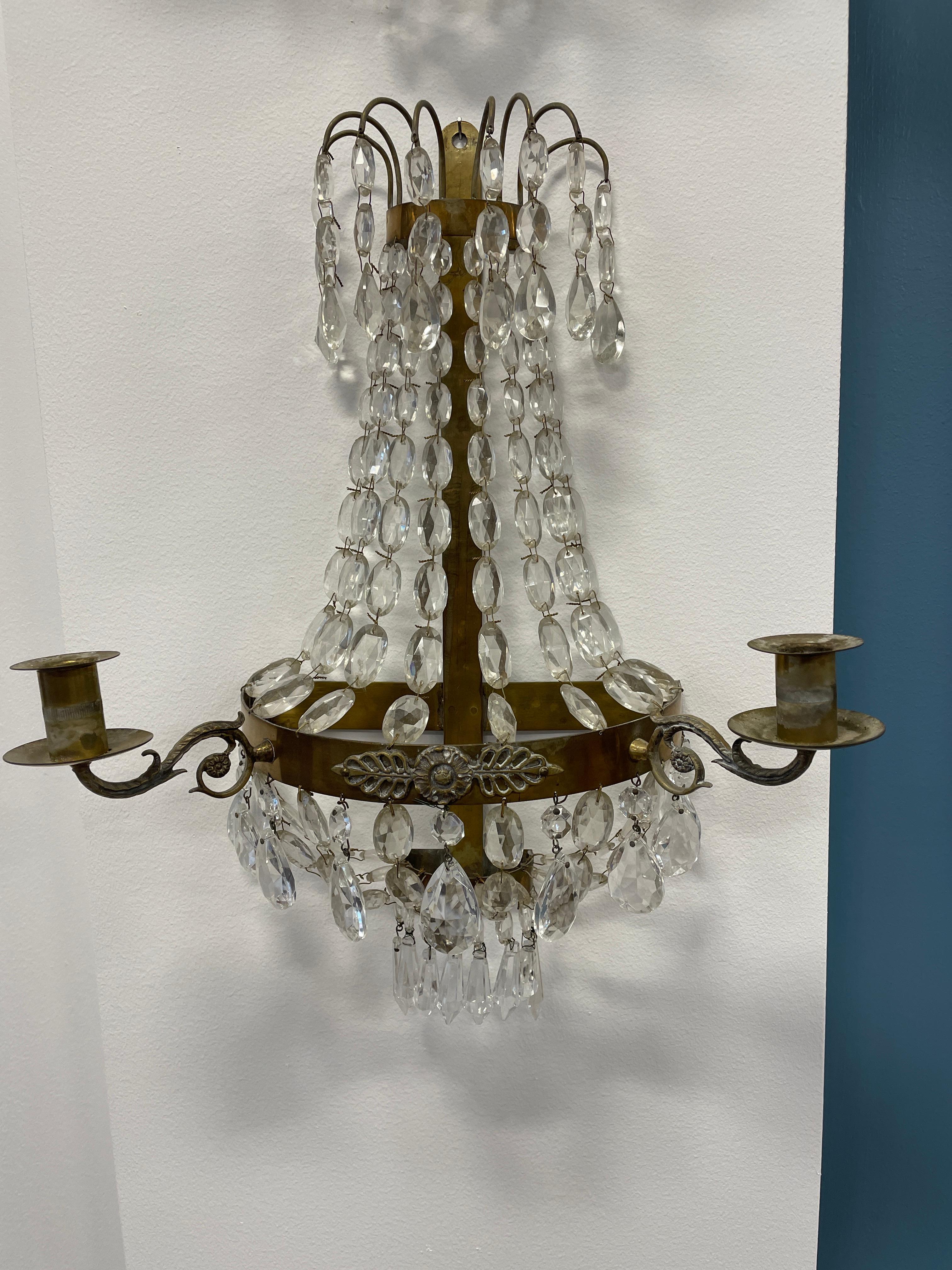 Discover the timeless elegance of a pair of antique Swedish Gustavian Glass Appliques, meticulously crafted from handcrafted brass and adorned with prism glass drops. These Scandinavian sconces, in good condition, boast two candle holders each,