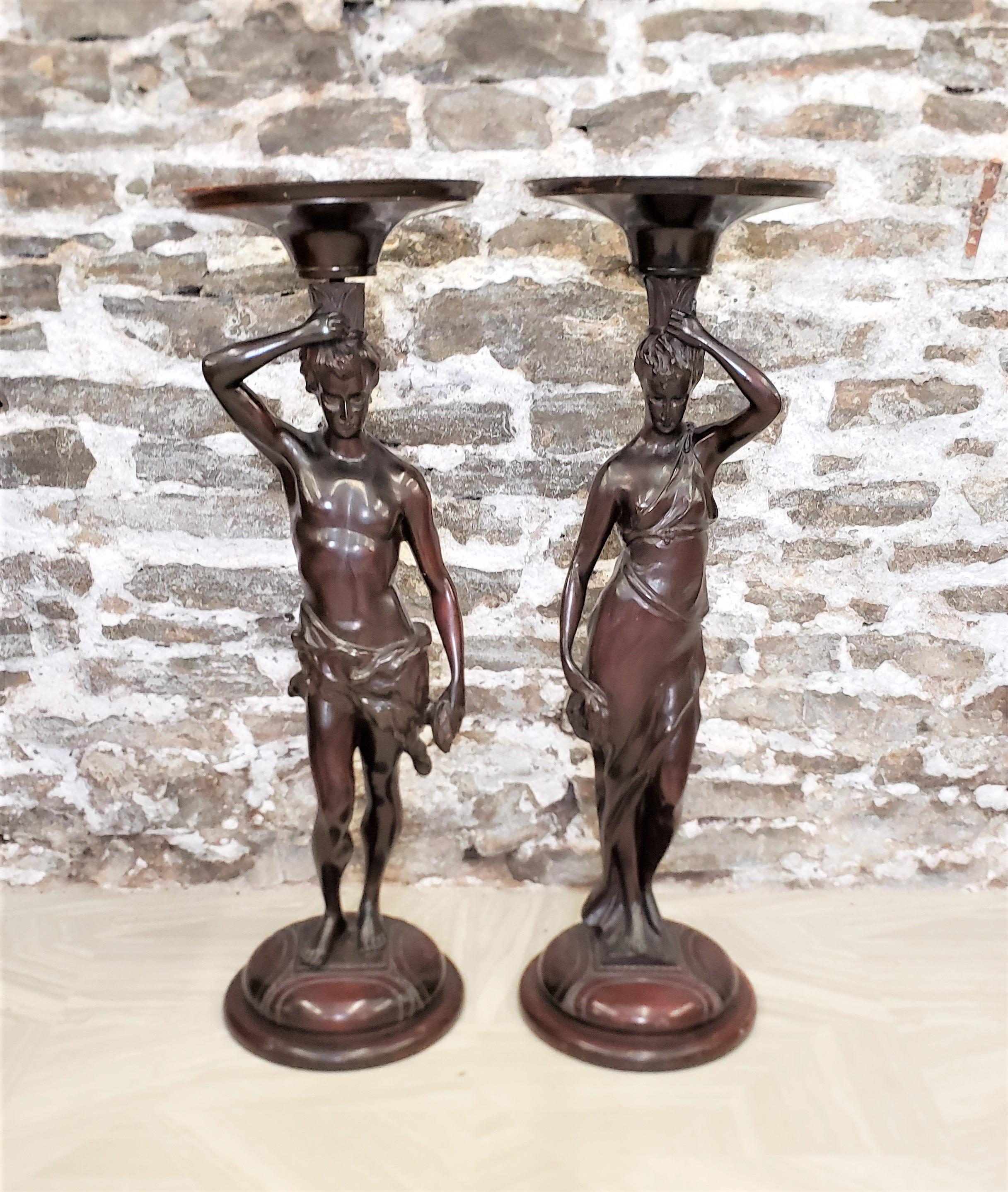 This pair of antique pedestals are unsigned, but presumed to have originated from the United States and date to approximately 1900 and done in a Neoclassical Revival style. The pedestals are composed of a hardwood that have been hand-carved to