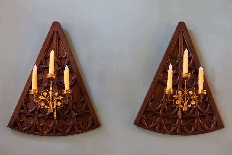Hand-carved oak trefoil and quatrefoil backplates with antique brass 3 arm candle holders. Circa 1890s. Oak back plates are 3/4