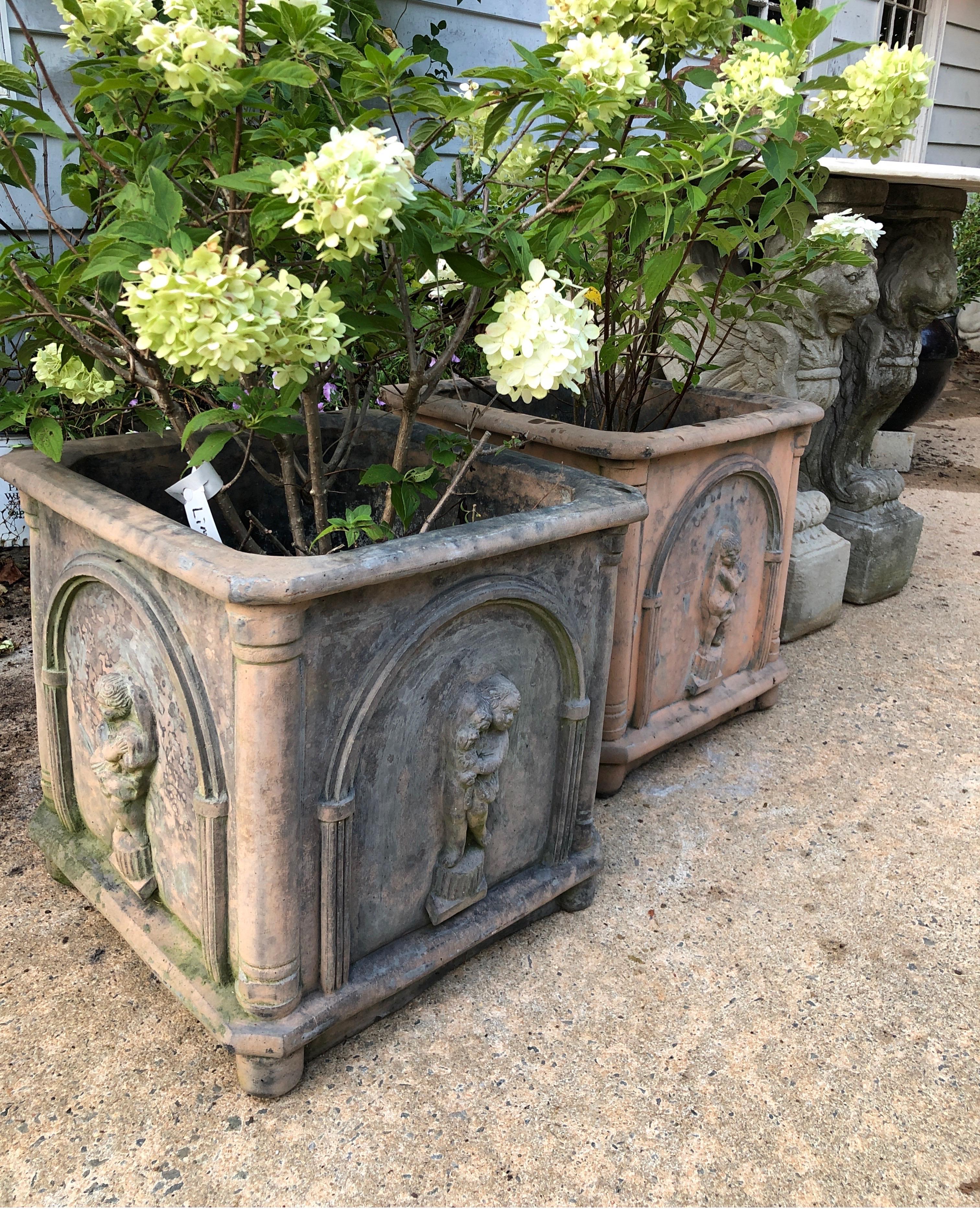 Pair of antique French planters with cherubs. One has more patina than the other (see images). These are a very heavy stone material.  Perhaps lead.

Measure approx 18 x 18 x 18.