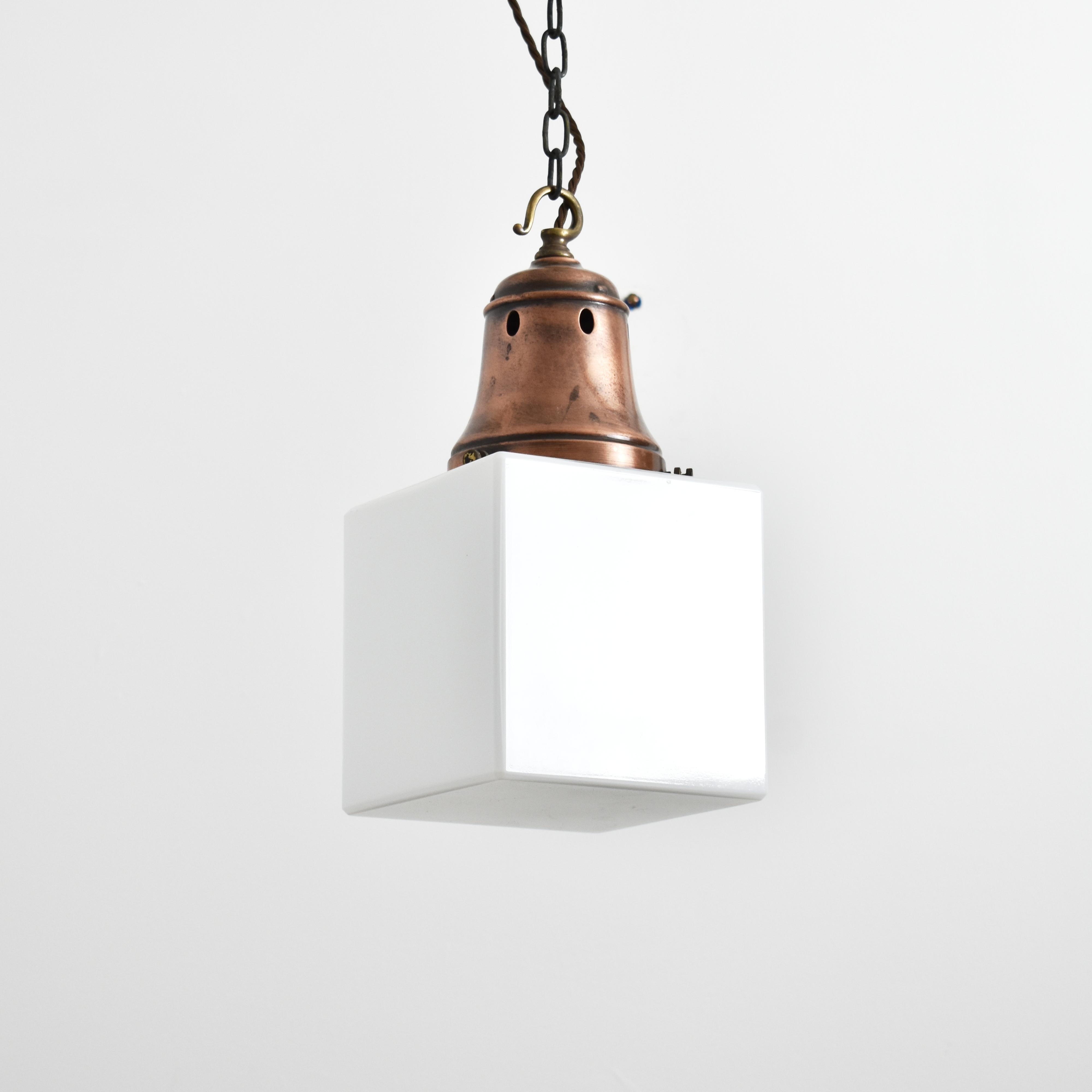 Coppia di lampade a sospensione a cubo opalino antico di Holophane

Un'insolita coppia di lampade a sospensione opaline antiche in stile art deco. Le luci hanno paralumi in vetro opalino a forma di cubo con bordi e corone smussate, gallerie in rame