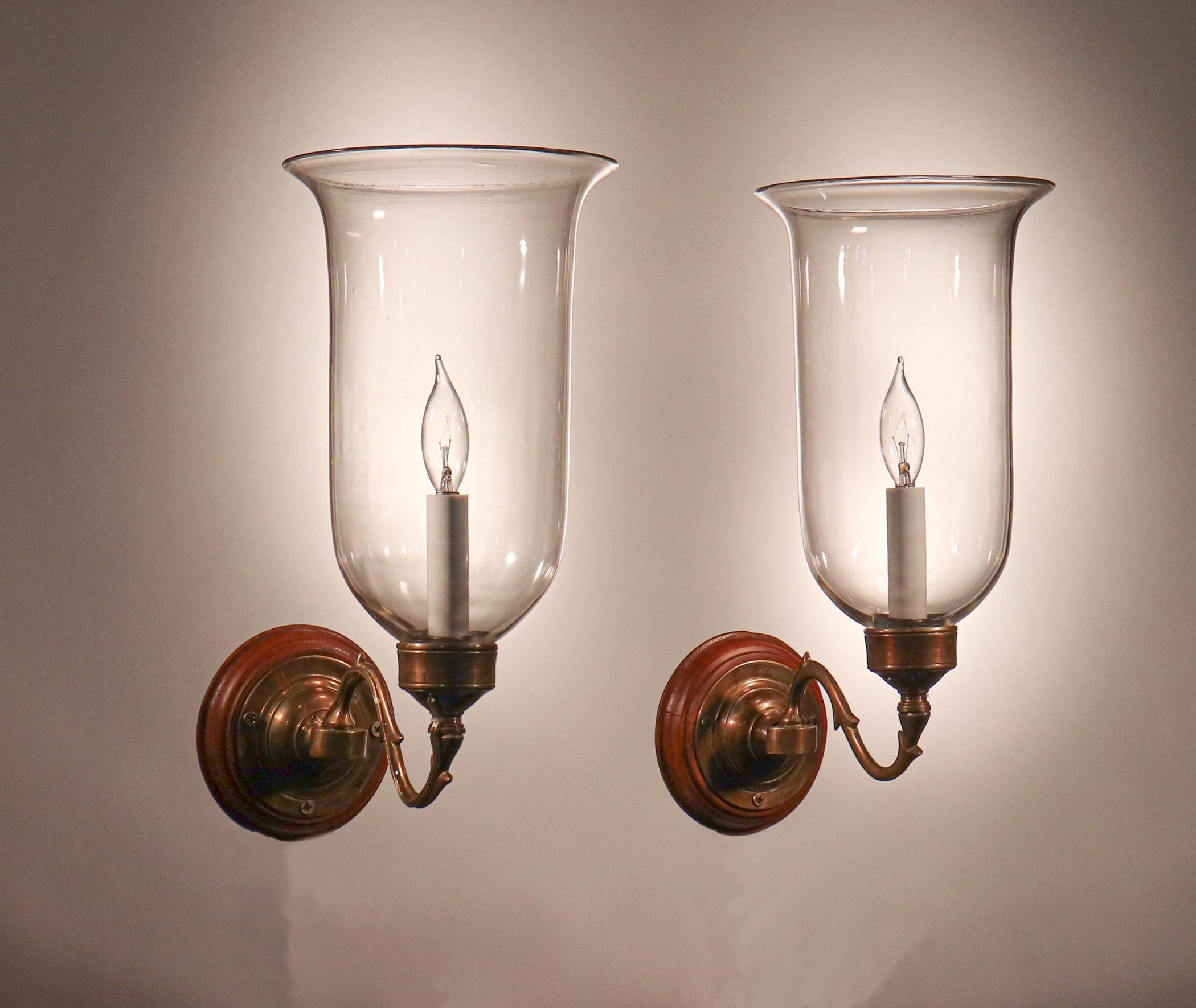 A classic pair of antique English hurricane sconce shades with nice form and a gentle flair. The quality of the hand blown glass is very good, with desirable swirls and air bubbles in both shades. These circa 1900 wall sconces have been newly