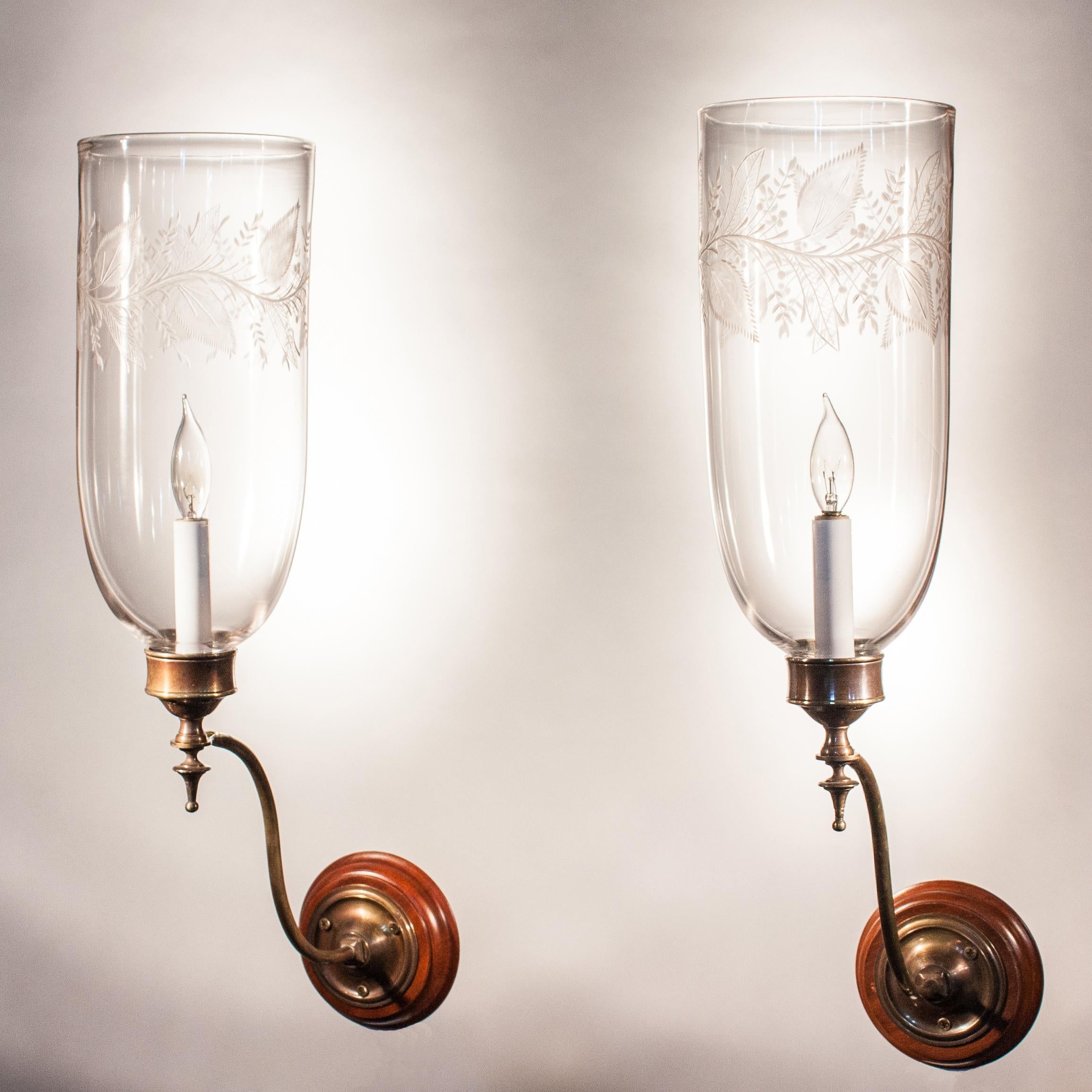 A pair of clear, hand blown glass hurricane shades manufactured by F.&C. Osler, England, circa 1880. The excellent quality shades have attractive lines that are accentuated by the etched leaf motif around the top. Custom-fabricated, Classic brass