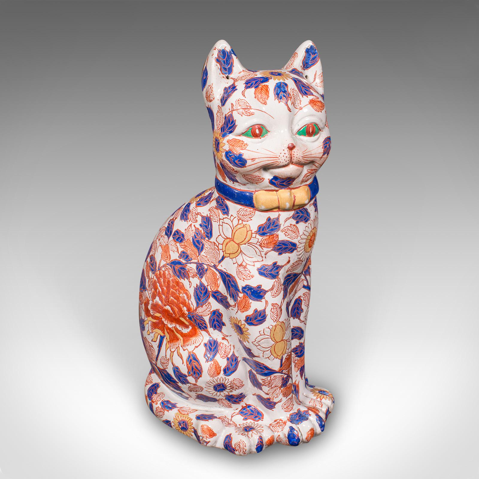This is a pair of antique Imari cat figures. A Japanese, ceramic fireside ornament or tall volume bookends, dating to the Edwardian period, circa 1910. Rich in personality and artistry, these feline companions bring an elegant decorative presence to