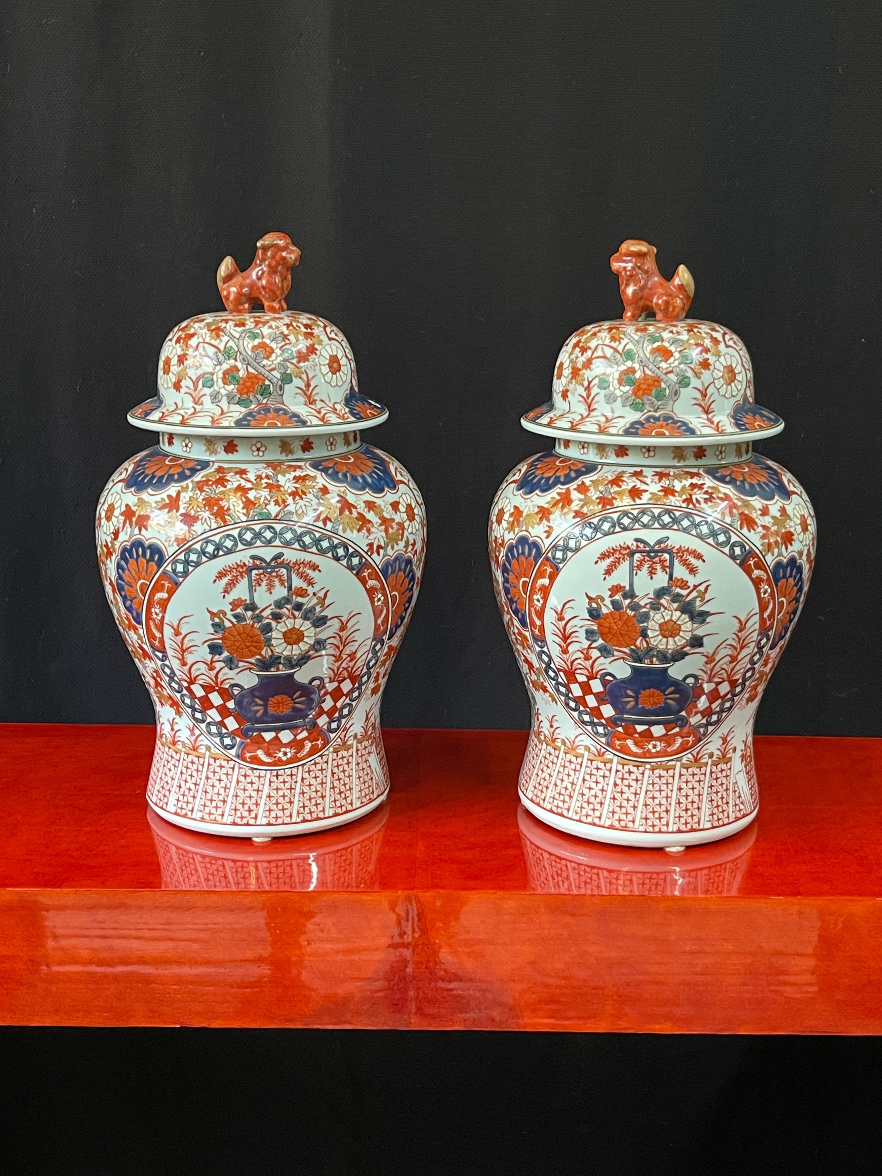 Exquisite pair of early 20th century Meiji Period Imari ginger jars with hand-painted designs on porcelain. The jars are decorated with a traditional Japanese Imari floral motif painted in enamels of intense iron red, red-orange, rich cobalt blue,