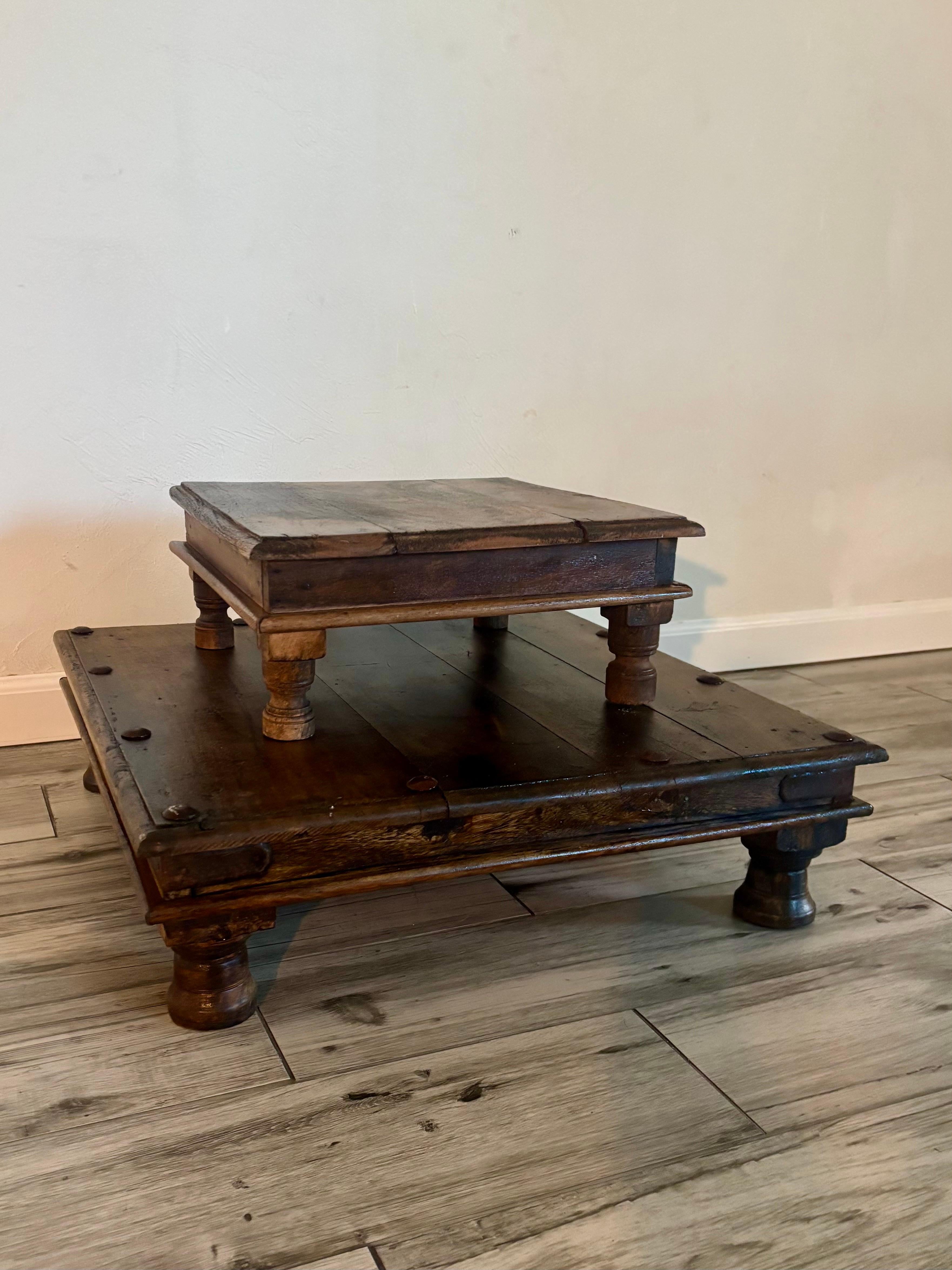 Paire de tables de prière indiennes de la fin du XIXe siècle d'une grande simplicité, taillées à la main dans du bois massif, avec une présence élémentaire et usée par le temps. De forme carrée et de profil bas, chacun repose sur quatre pieds