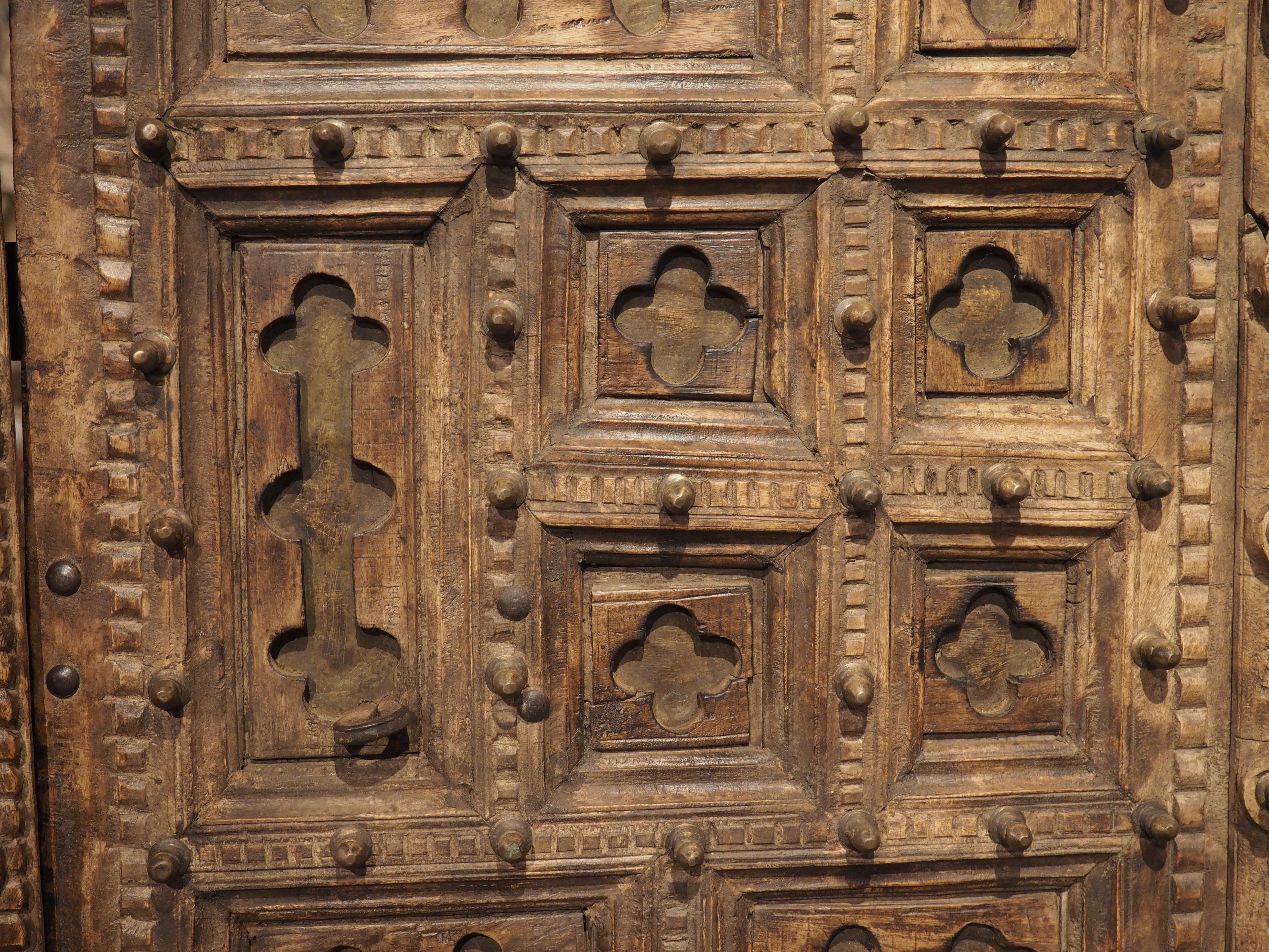 This pair of antique doors was hand-carved from teakwood in India during the 1800’s. The tall and slender doors are adorned with rectilinear panels of various sizes and orientation. Each quadrilateral features cavetto molding and has been incised