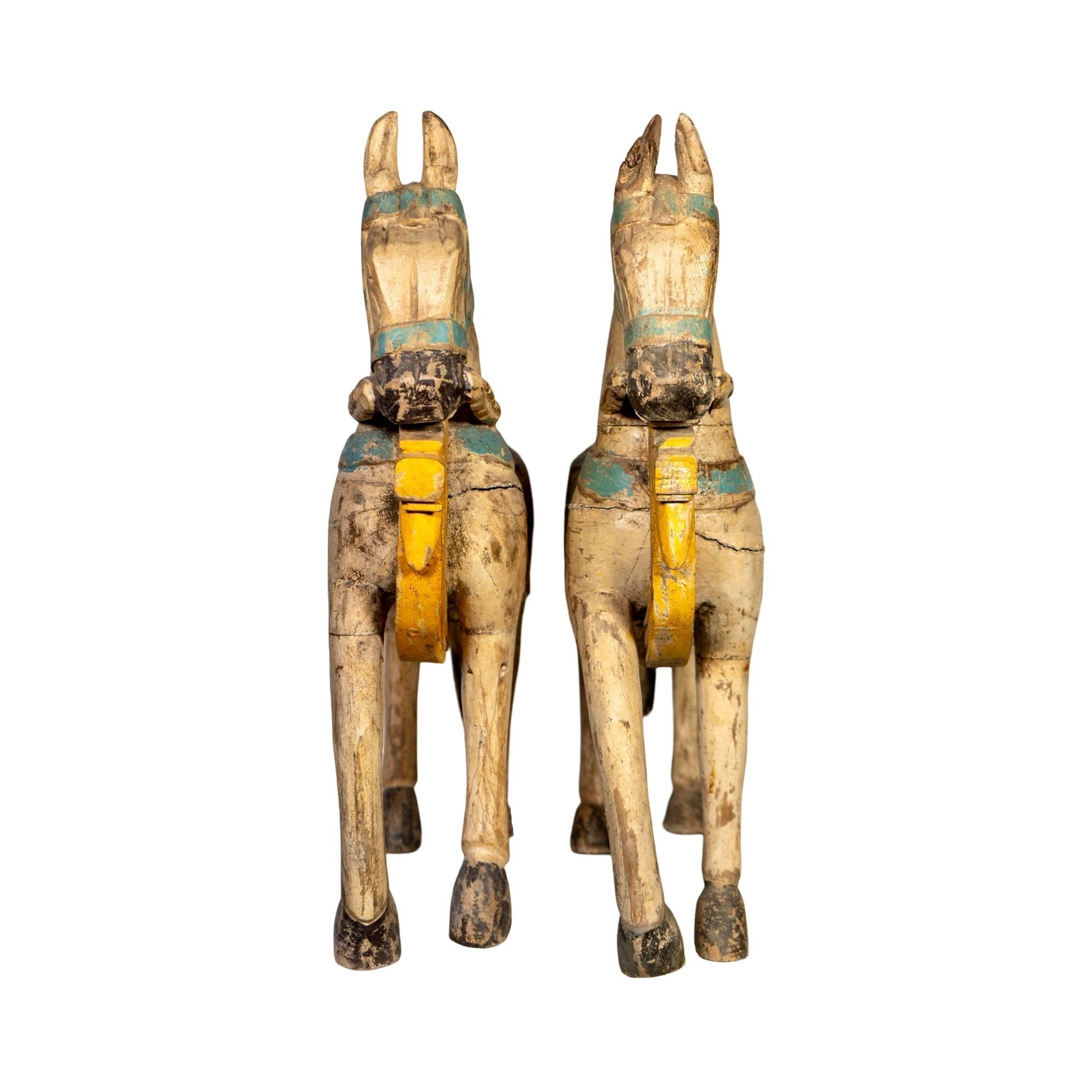 A pair of antique wooden horse sculptures from India, dating to the early 1920s. Adorned in vibrant, multi-colored painted finishes, each piece carries the charm of timeworn artistry. Sold as a pair, they’re ideal for adding a touch of old-world