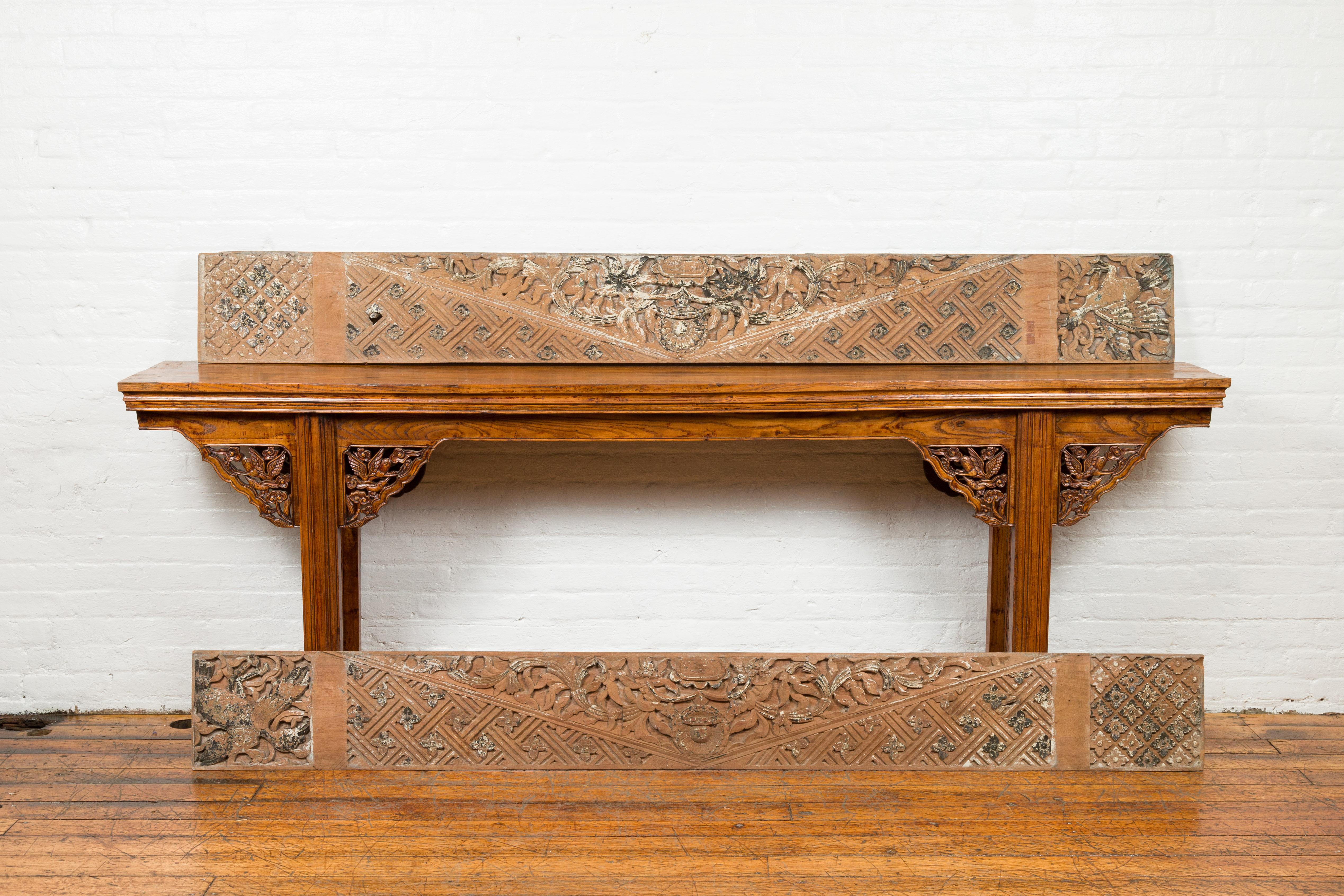 A pair of antique Indonesian carved wooden panels from the 19th century, with traces of original paint. Crafted in Indonesia, each of these horizontal carved panels features geometric motifs surrounding a delicate scrolling foliage, accented with