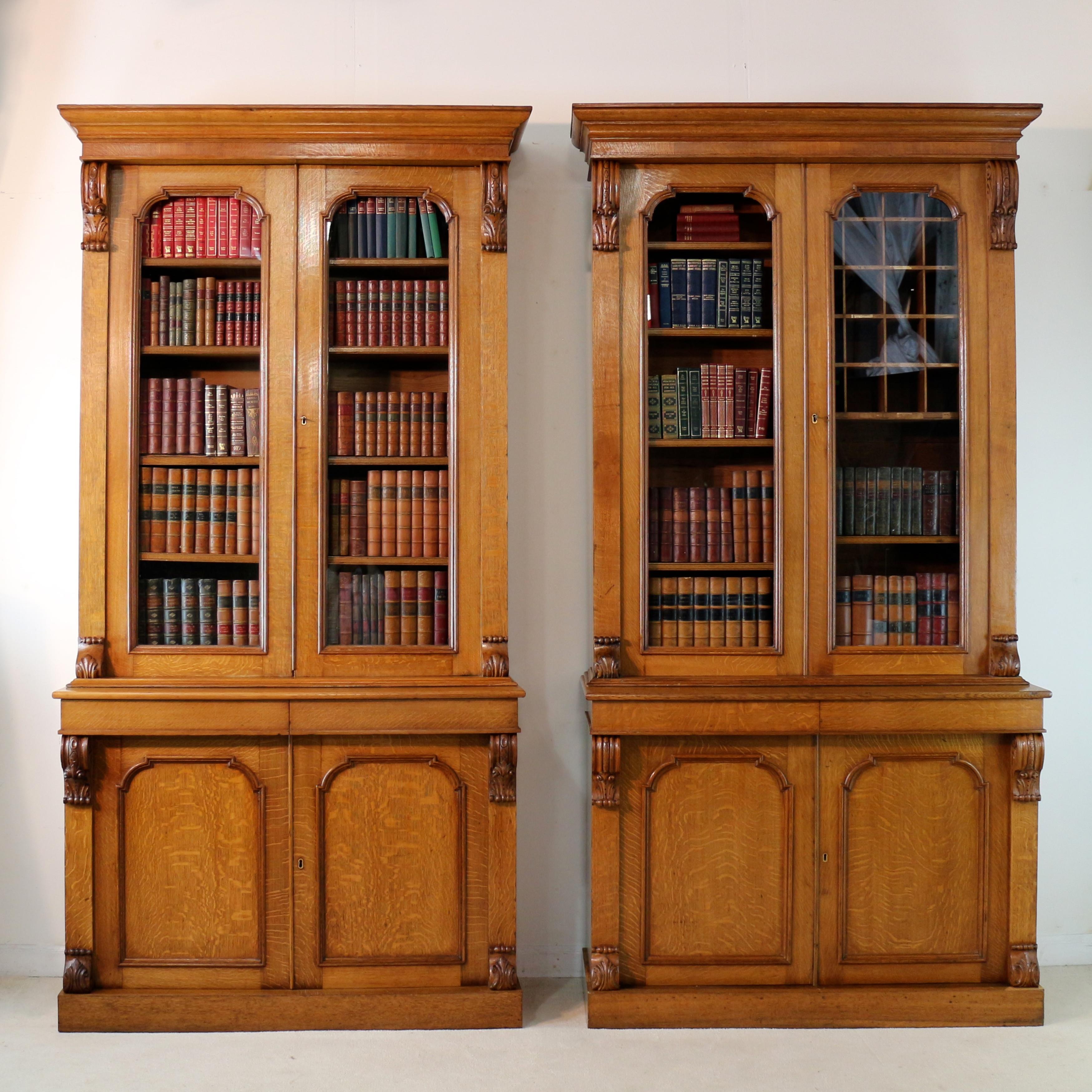 A rare pair of Irish William IV estate library bookcases by J J Byrne of Dublin. In golden quarter-sawn oak with attractive ‘tiger grain’ or medullary rays. Featuring decorative carved scrolling corbels, each has a square cornered moulded cornice