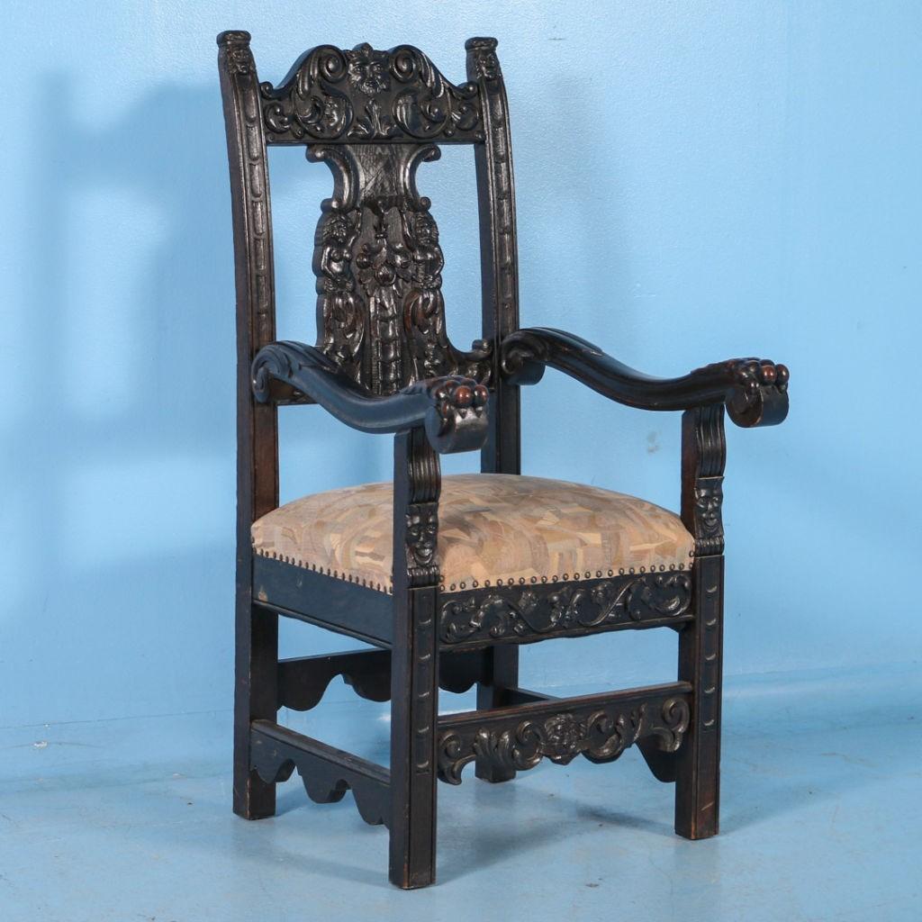 This grand pair of antique upholstered Italian oak armchairs are carved with remarkable details in relief. The backrest is covered with a number of carved motifs from ribbons, flowers and masks to a pair of human figures. The arms end in a lion's