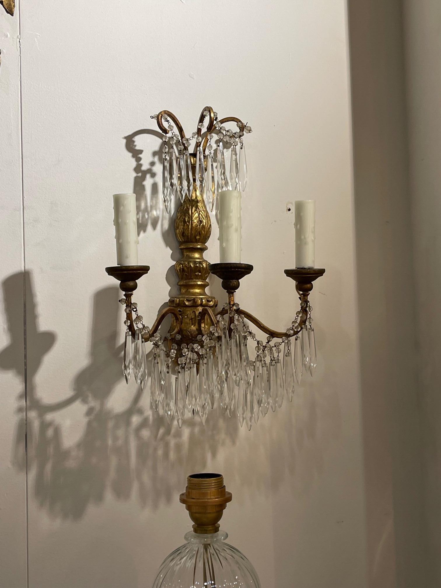 Very fine pair of antique Italian giltwood and crystal 3 light wall sconces. This pair has a pretty carved base along with beautiful dangling crystals. Creates a classic look!.