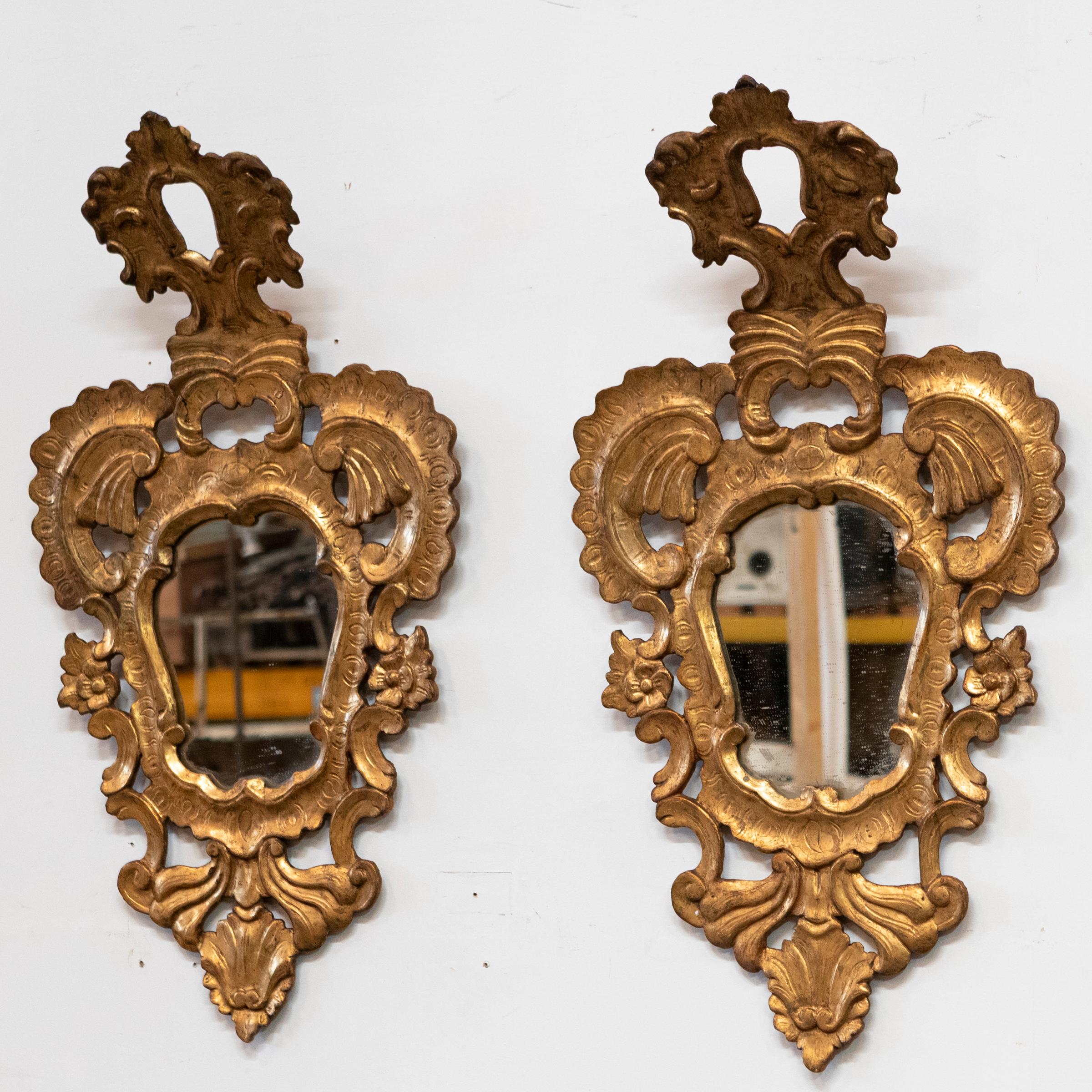 Specchi da parete italiani altamente decorativi. 

L'antica coppia presenta cornici in legno dorato riccamente intagliate e ornate da intricati motivi a volute, foglie d'acanto e conchiglie, coronate da scenografiche creste sporgenti.

Ogni specchio
