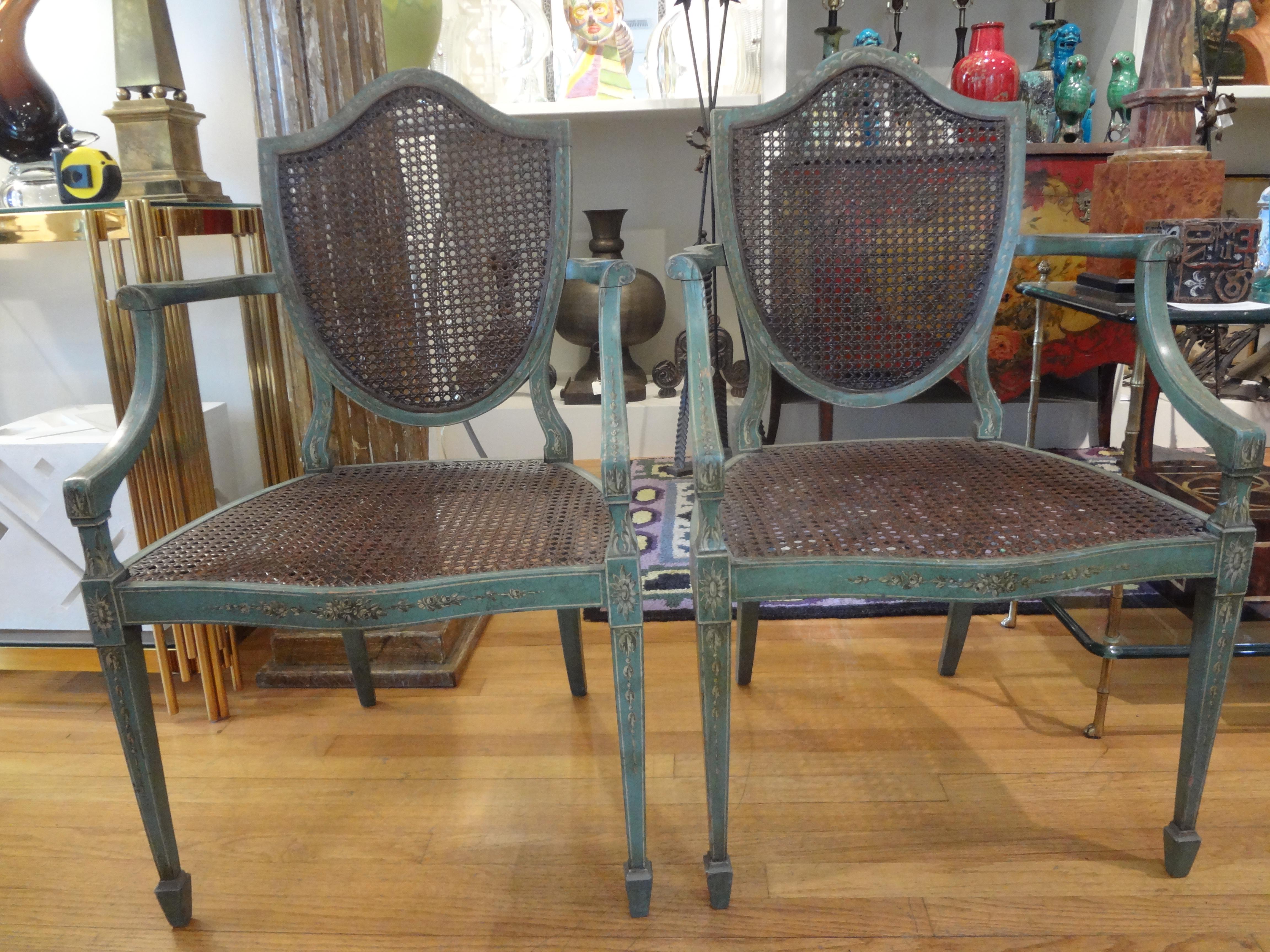 Stunning pair of antique Italian Louis XVI style teal colored shield back chairs with cane backs and seats. These Italian neoclassical style host chairs, side chairs or armchairs are painted a lovely shade of teal hand decorated with delicate vines