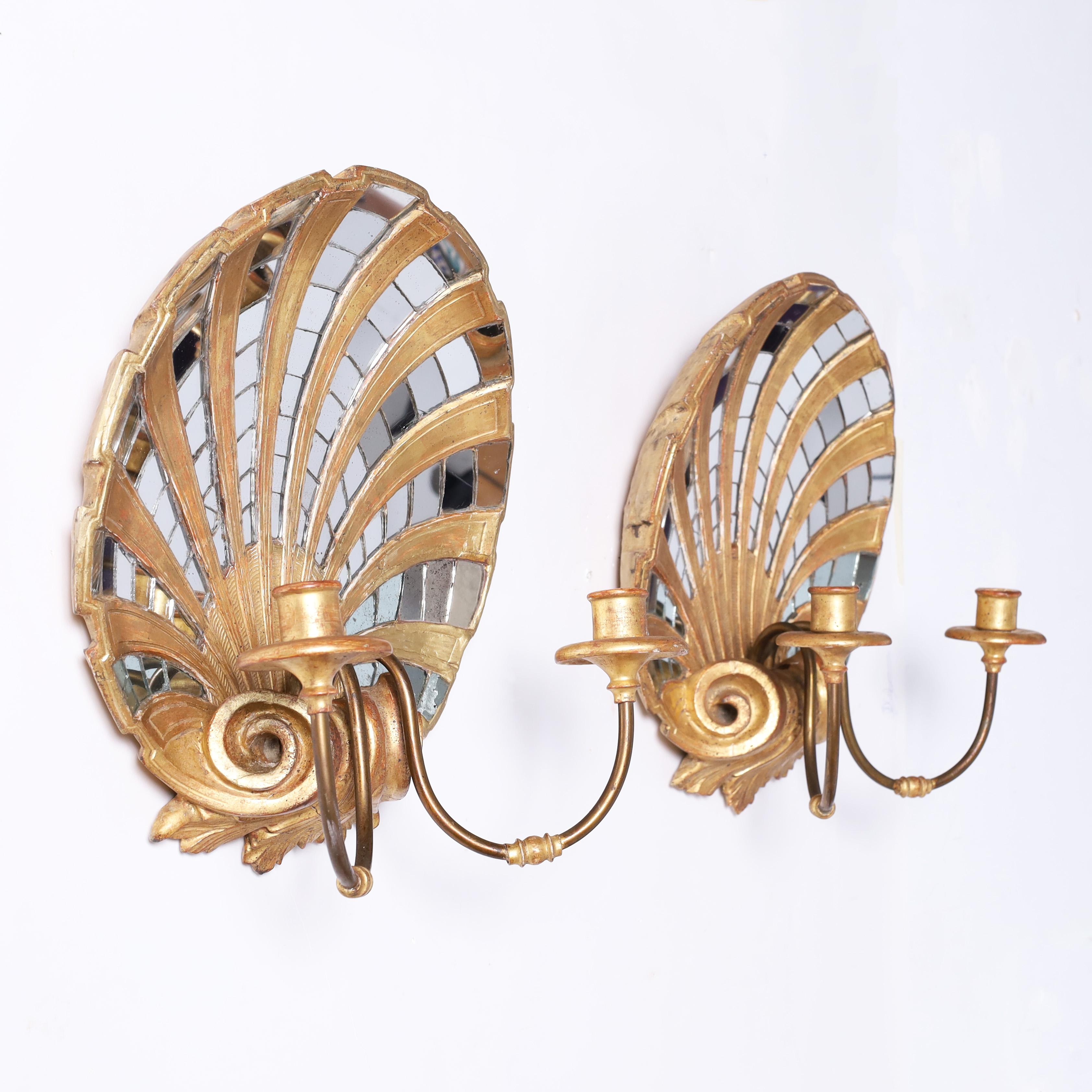 Enchanting pair of Italian grotto style wall sconces hand crafted in carved wood in a neoclassical gilt shell motif decorated with a mirror mosaic over two elegant metal arms with gilt wood candle cups.