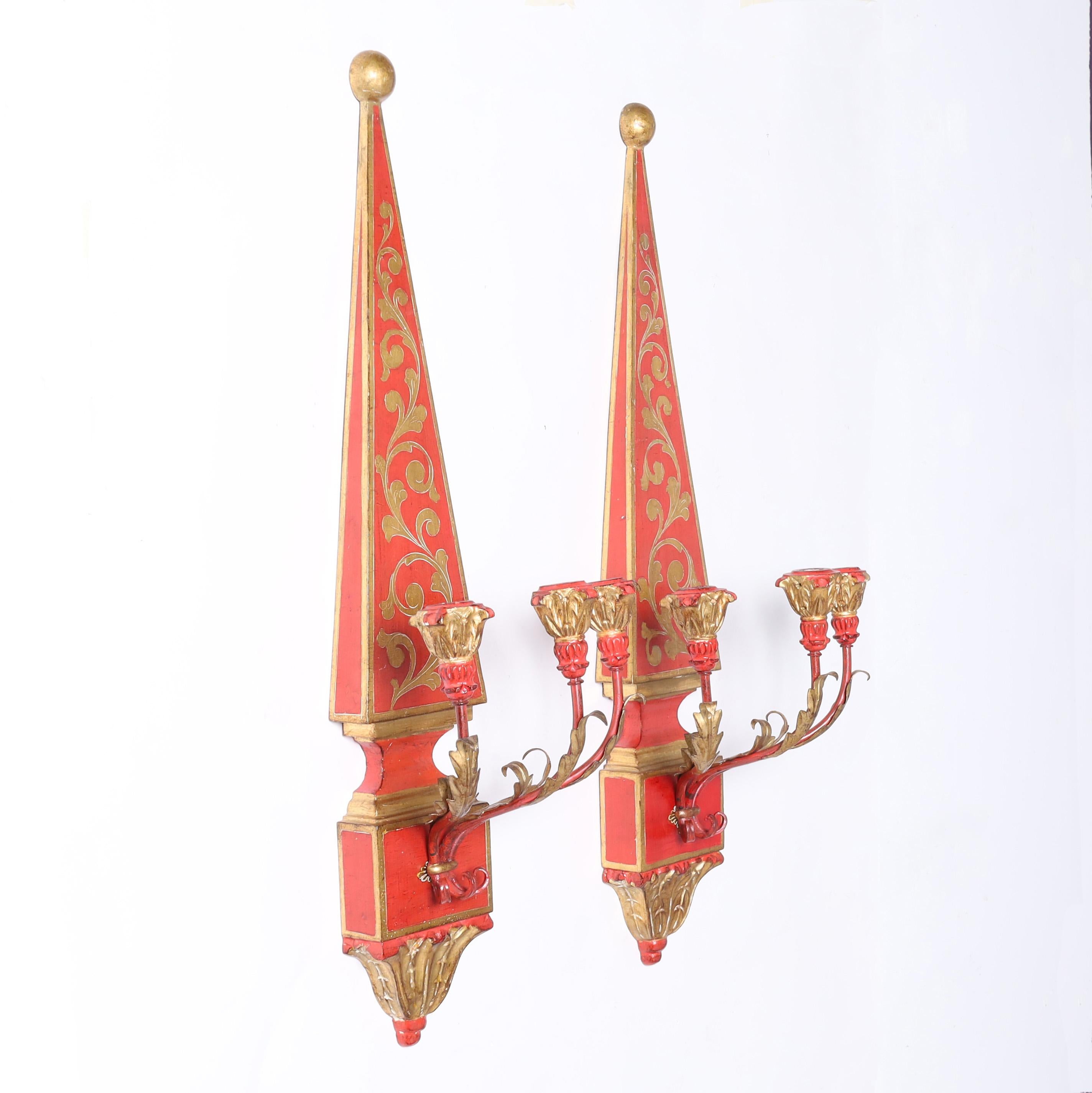 Striking pair of Italian wall sconces crafted in wood in classic form decorated with gilt floral designs over an alluring red background with three metal arms having gilt acanthus leaves and carved wood gilt candle cups.