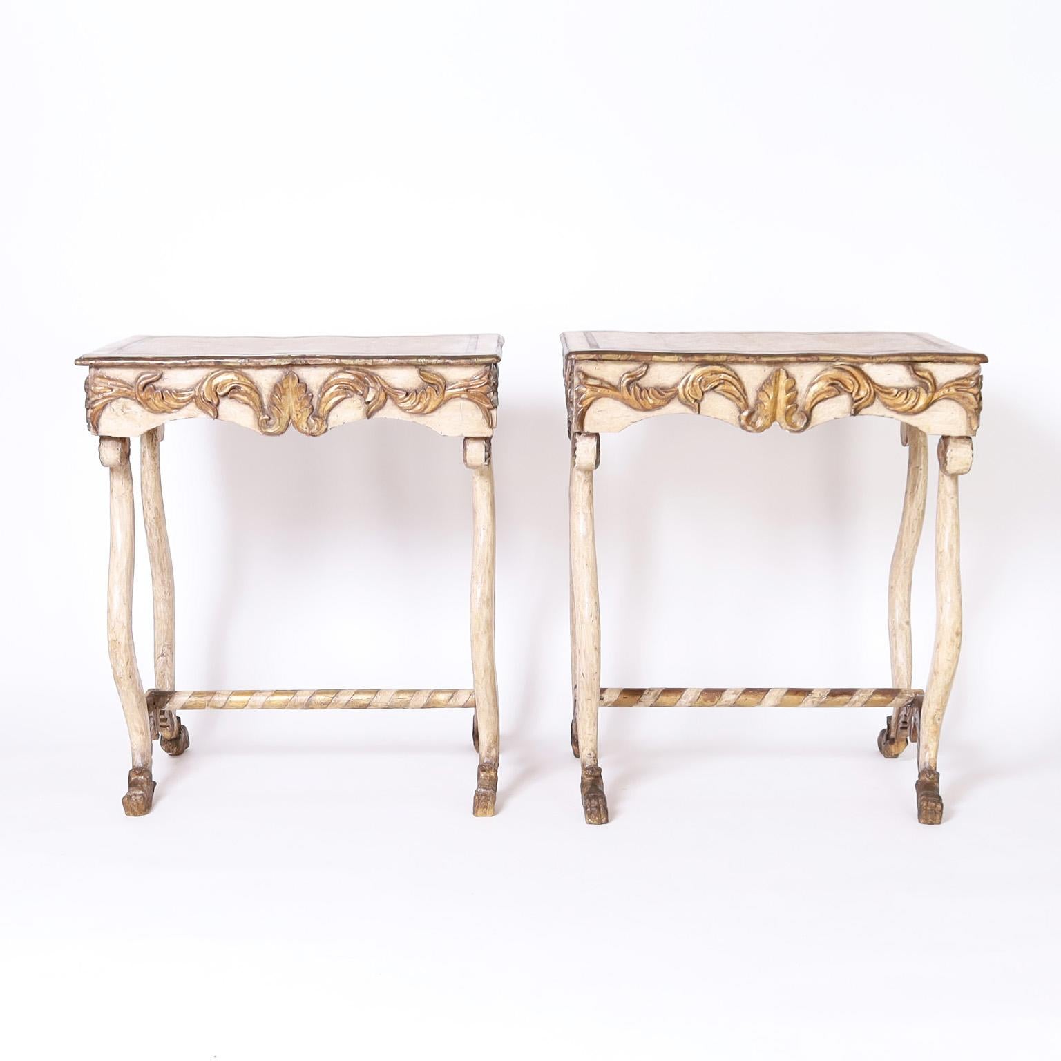 Delightful pair of late 18th or early 19th century Rococo Italian tables or stands crafted in walnut with a dramatic form. Hand carved and joined then painted, now fly specked, over gesso with gilt highlights.
