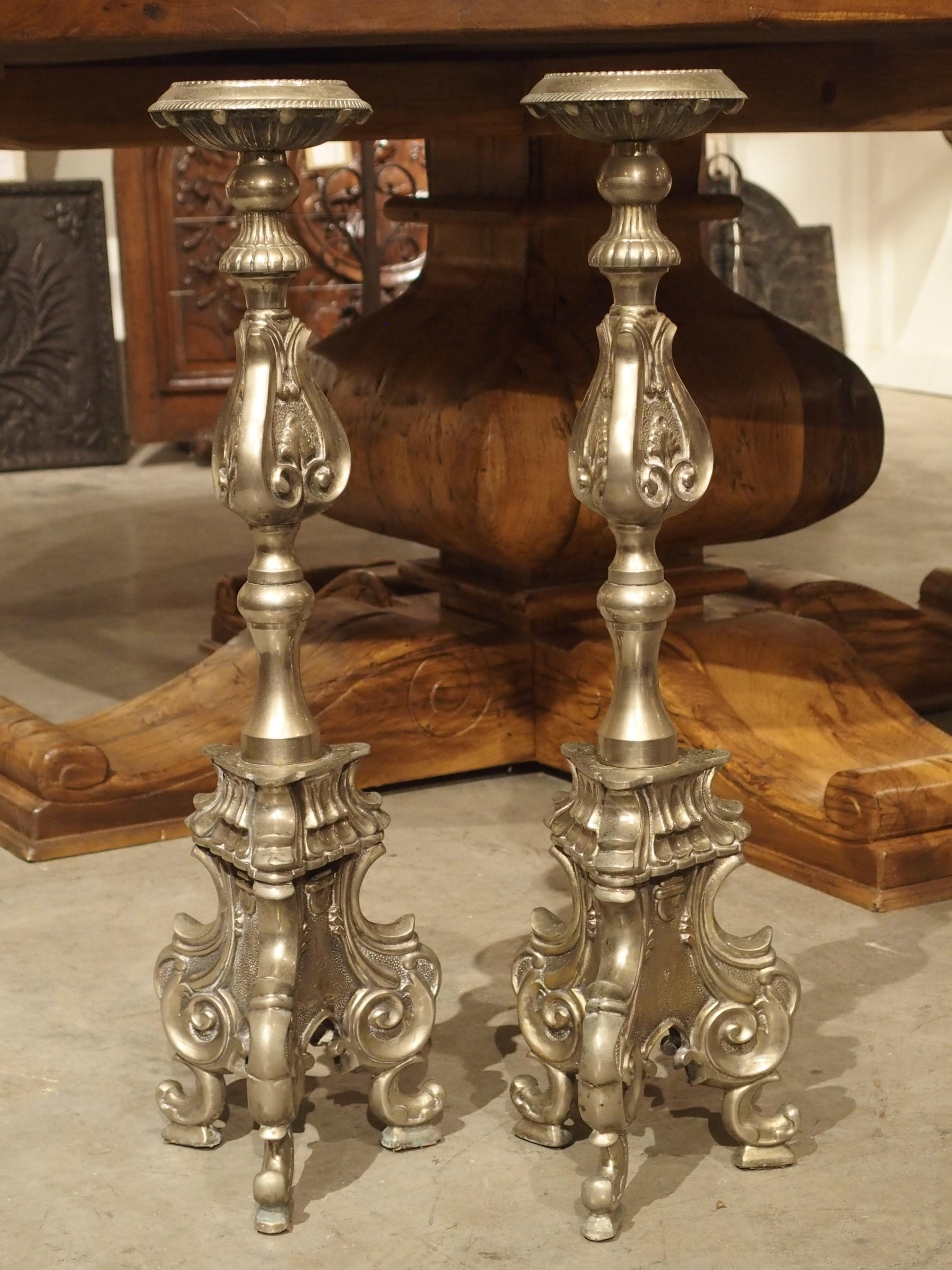 This pair of ornate silvered bronze candlesticks is from Italy, circa 1880. Each candlestick has a large round candle platform with beading on the interior rim and spiral fluting on the outer edge. Each can hold candles up to 3 1/2 inches in