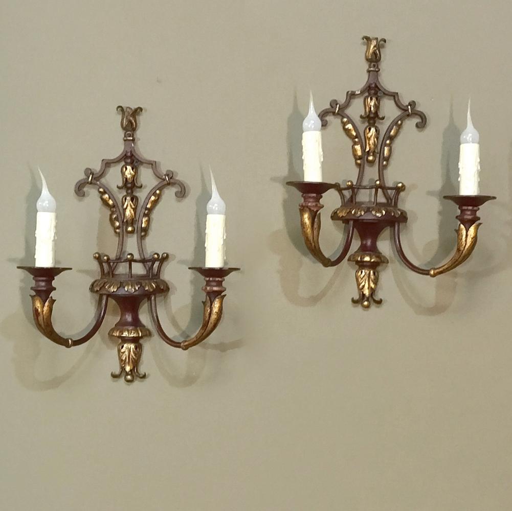 Pair of Antique Italian Wrought Iron and Painted Wood Sconces features a subdued burgundy color accented with gold on the hand-carved acanthus foliates.  The design intertwines upward and downward oriented foliate plumes with the pair of arms