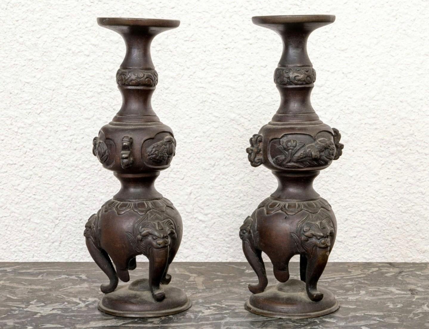 Coppia di candelabri d'altare in bronzo del periodo Meiji (1852-1912) con un'attraente patina di colore rosso bruno. 

Giappone, XIX secolo, piccola scultura a bulbo con maschera di drago e rilievi floreali, che si erge su gambe cabriole a tronco di