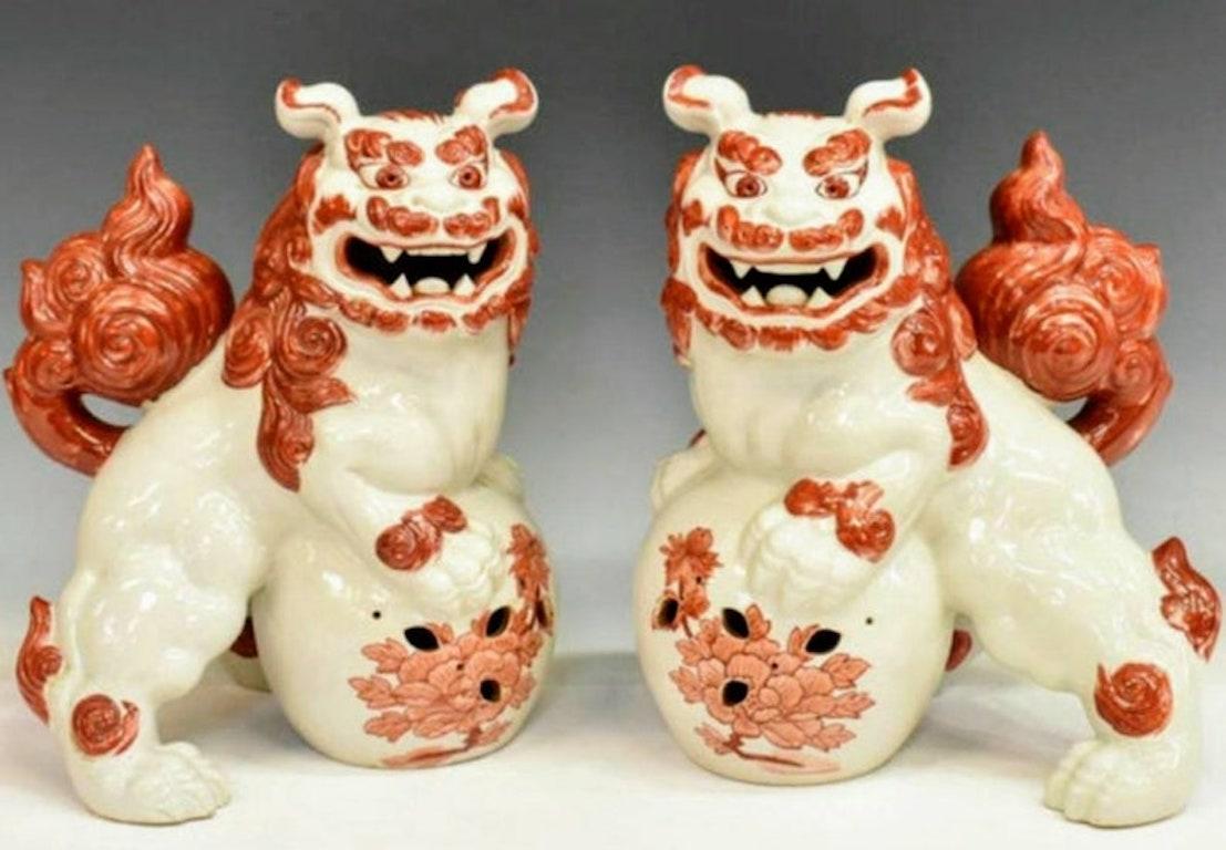 A fabulous mirrored pair of Kutani foo dog shishi / Buddhist temple guardian lions, hand-crafted in Japan during the Taisho period, the early 20th century Kutani porcelain sculpture figures in Blanc De Chine, accented with iron red glaze. Whimsical,