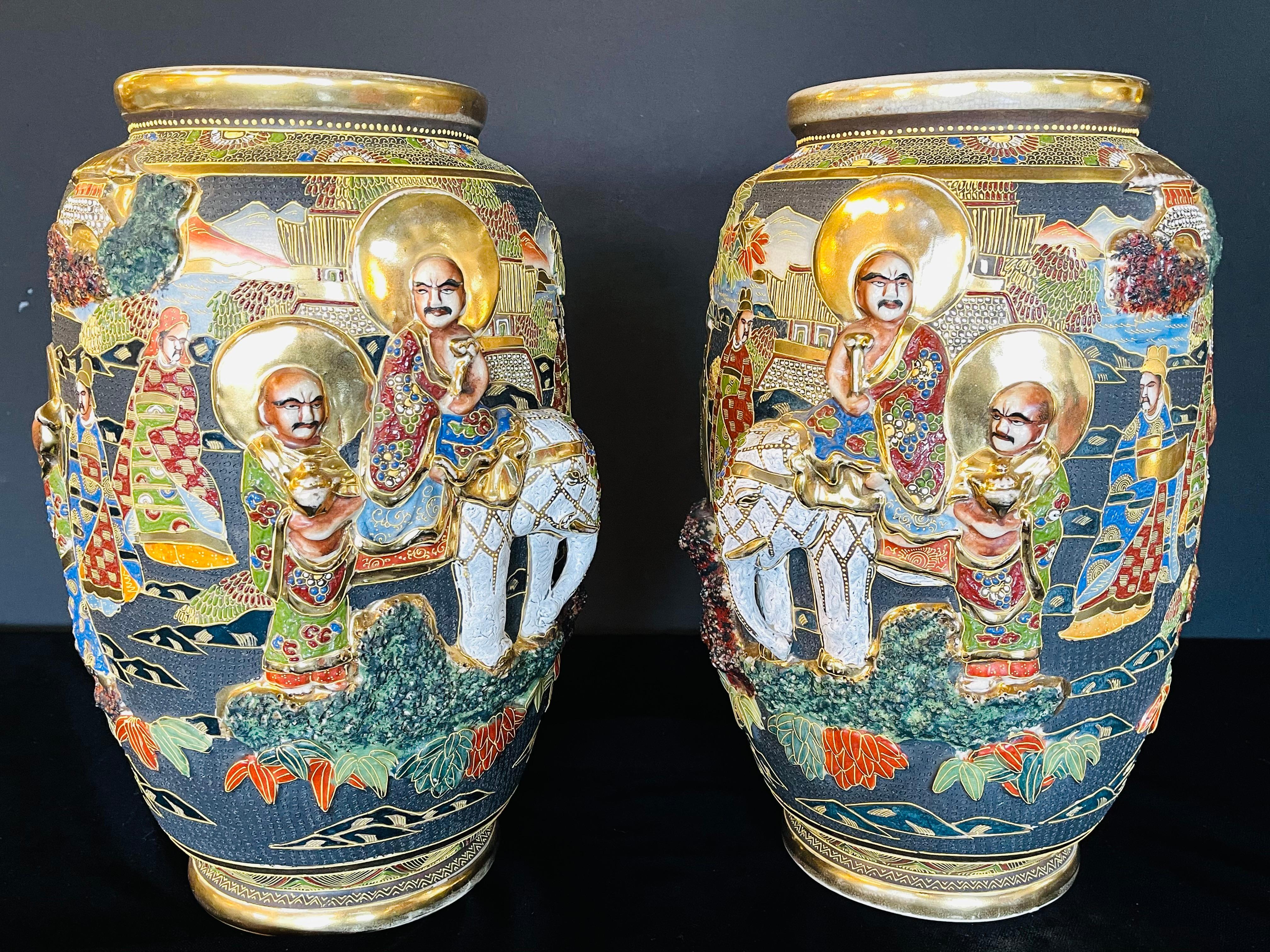 Pair of antique Japanese Satsuma vases. Each with opposing Scenes of figures and raised elephants. The pair in good condition.