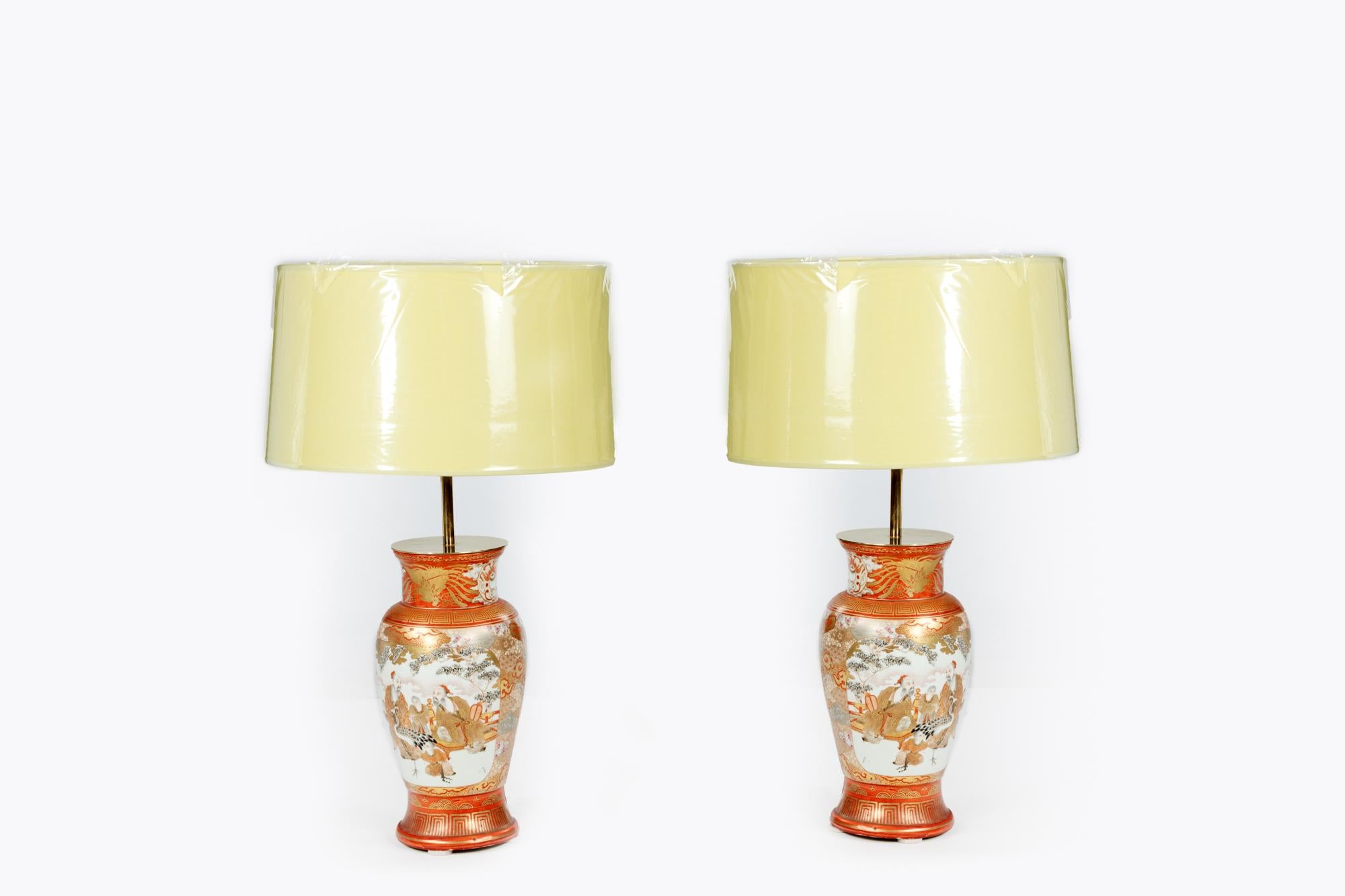 Pair of antique Japanese vases converted into table lamps complete with matching contemporary shades. They have been decorated in the traditional taste and feature geometric cartouches on both the rims and bases. Both display garden scenes showing