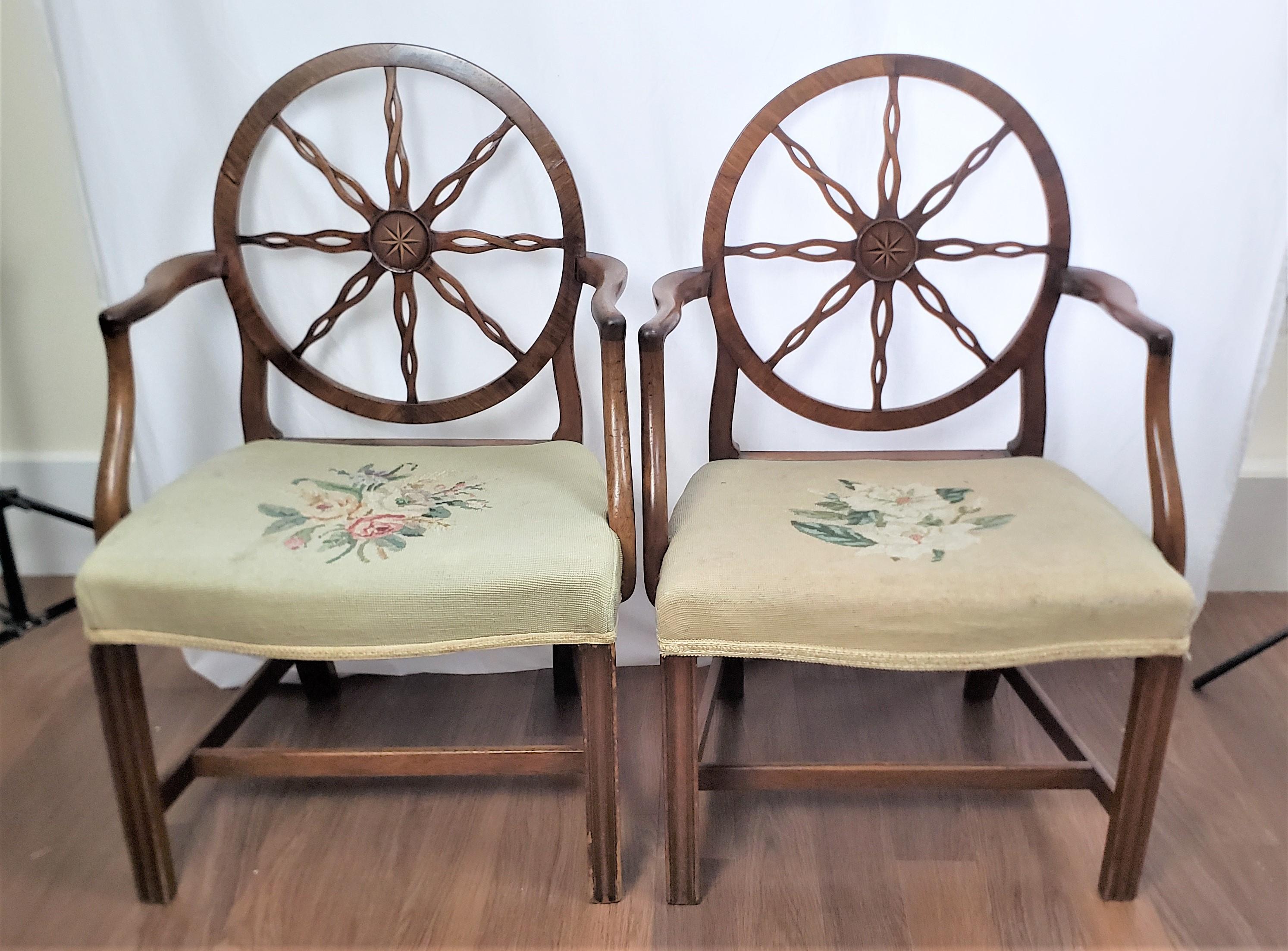 This pair of antique armchair frames are unsigned, but presumed to have originated from England and date to approximately 1790 and done in the period King George III style. The chairs are composed of walnut and feature a large spoked wheel back with