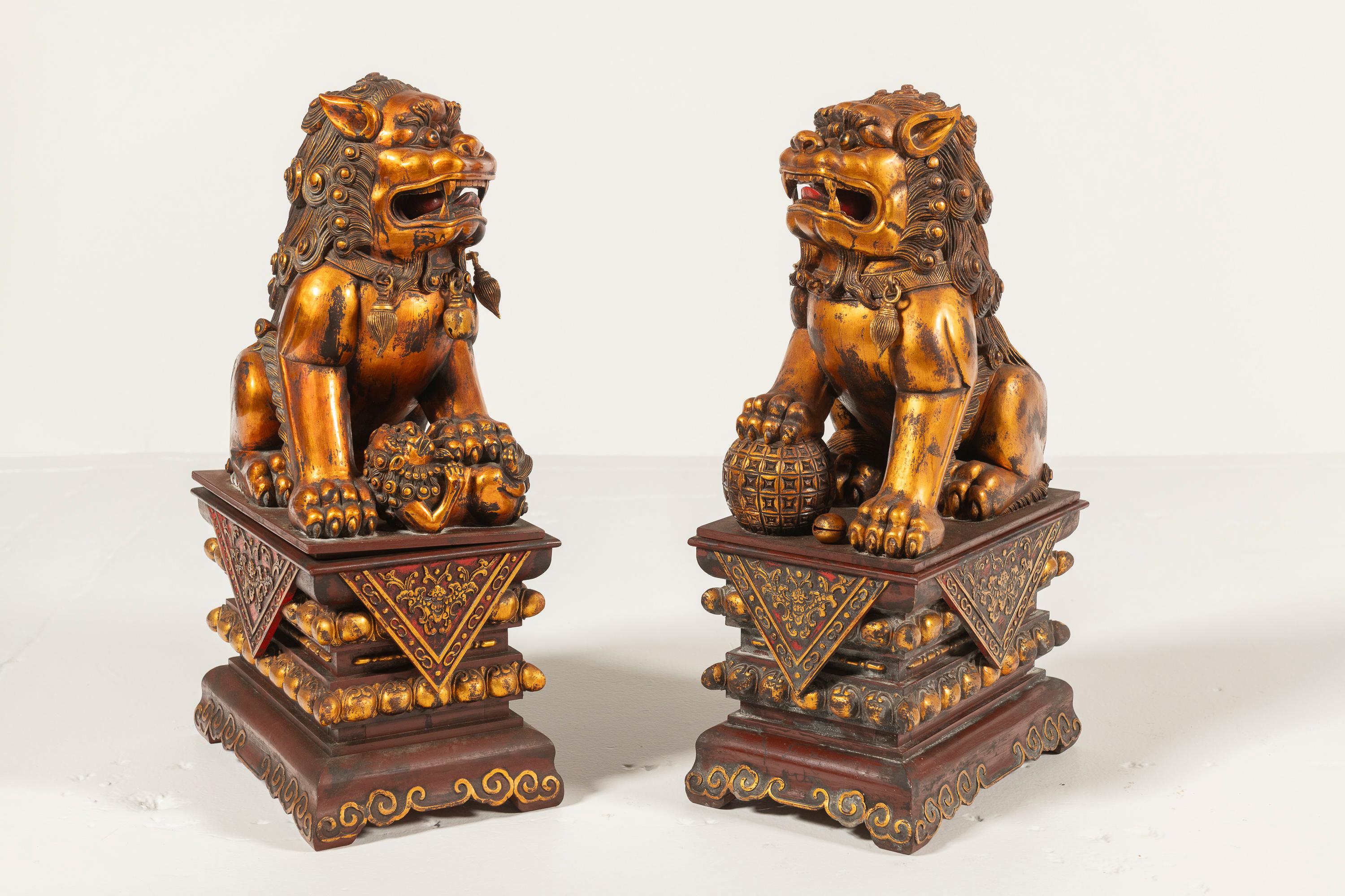 Foo Dogs, or Guardian Lions, are a Chinese symbol of protection, often placed at entrances to ward off evil spirits and attract luck and wealth. This antique wooden pair, with gilt detailing, is in good condition with a rich patina.